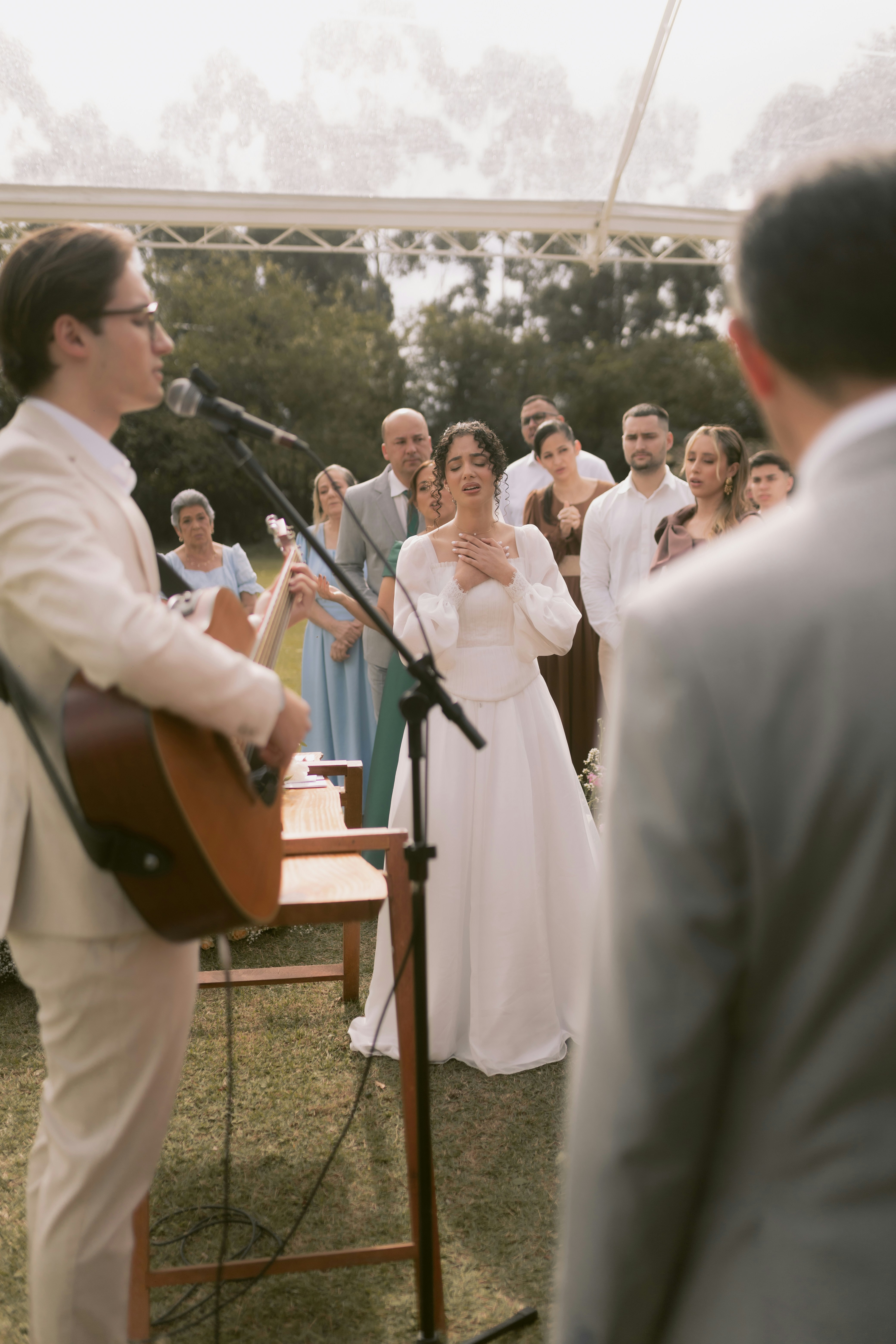 A bride listens to a song during an outdoor wedding.
