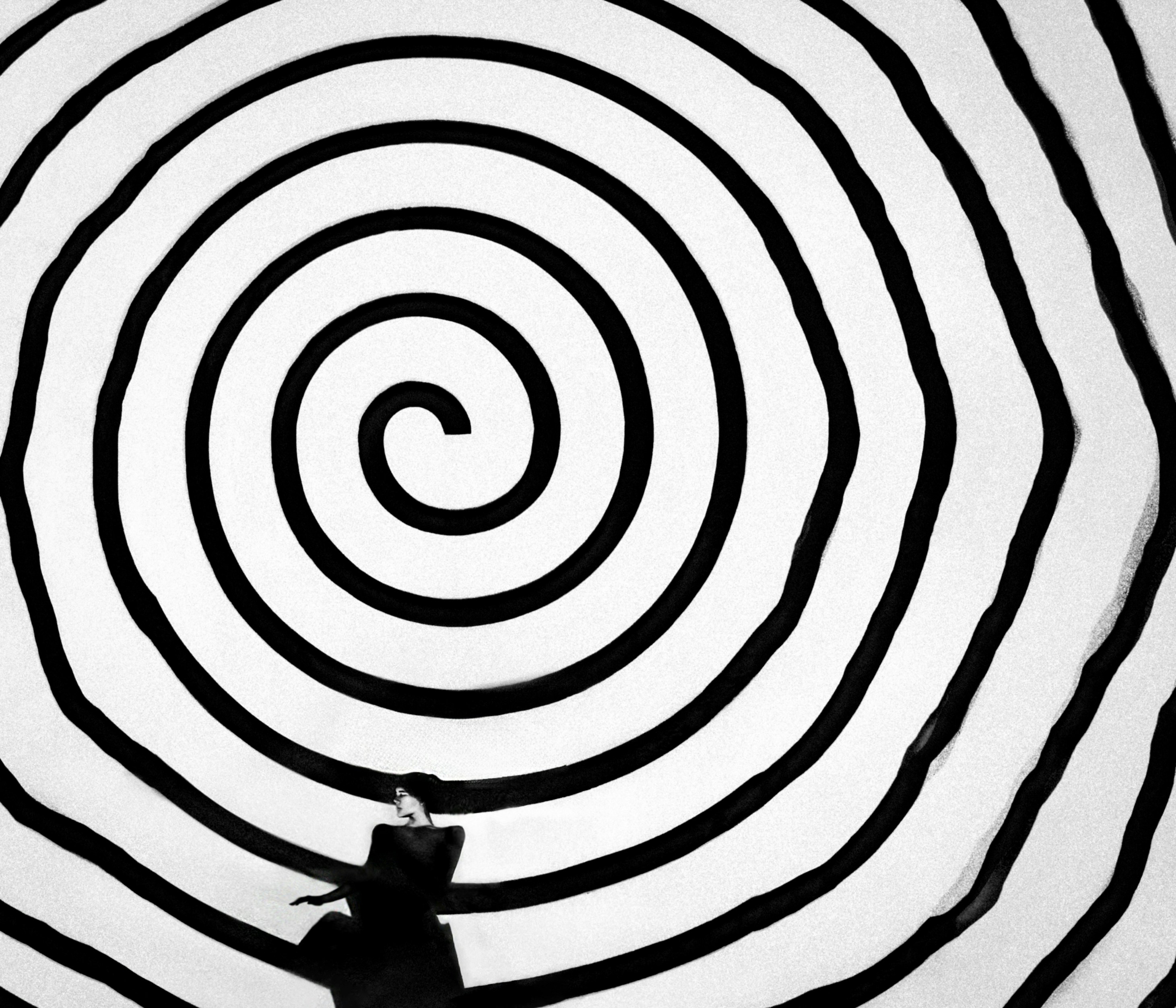 A person stands before a hypnotic spiral.