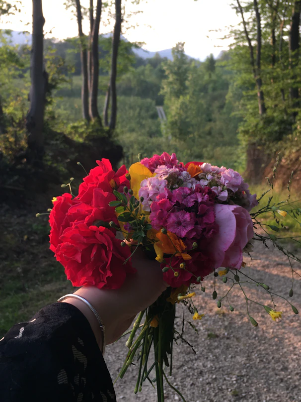 A hand holds a beautiful bouquet of flowers.
