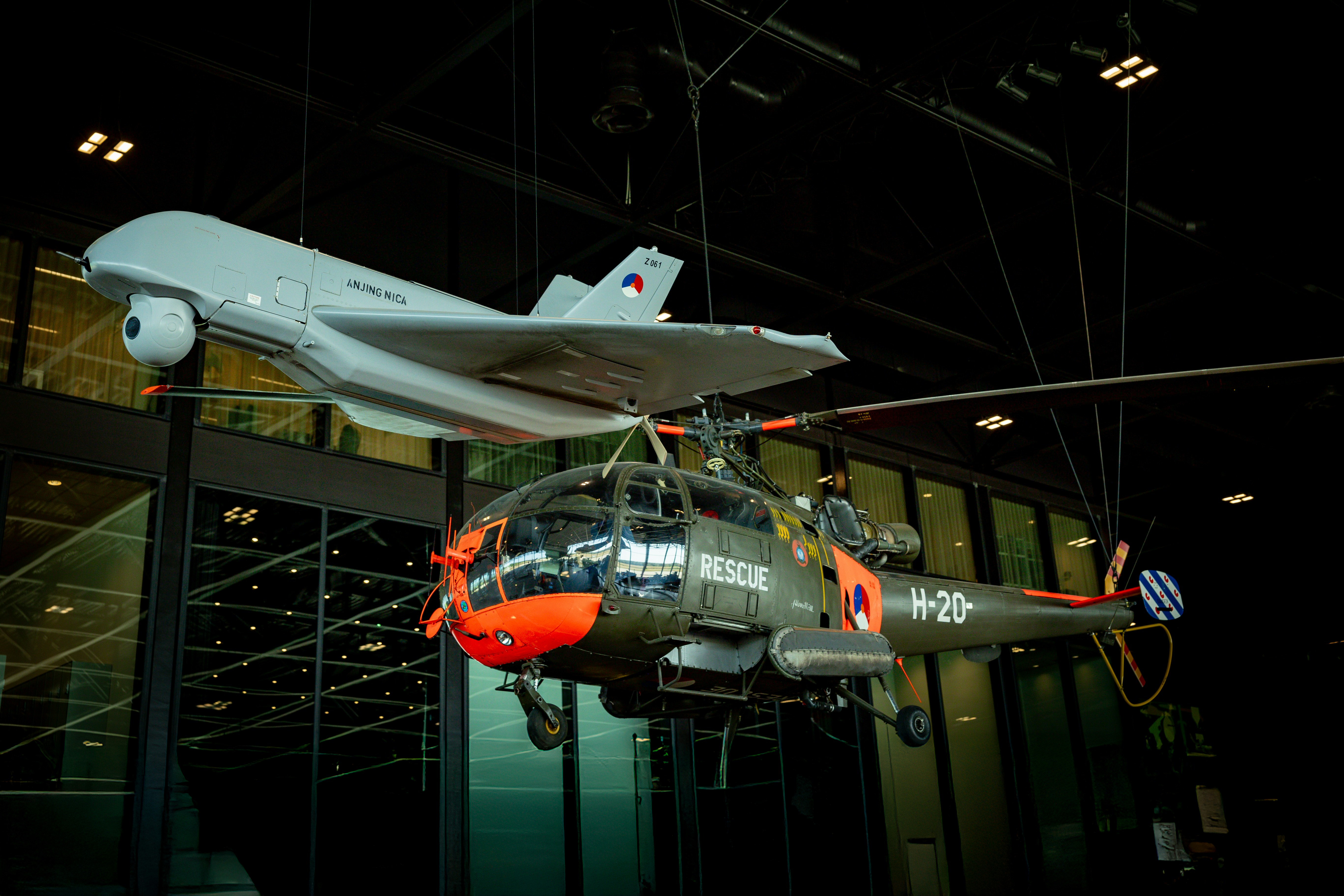 Military aircraft and a drone hang in display.