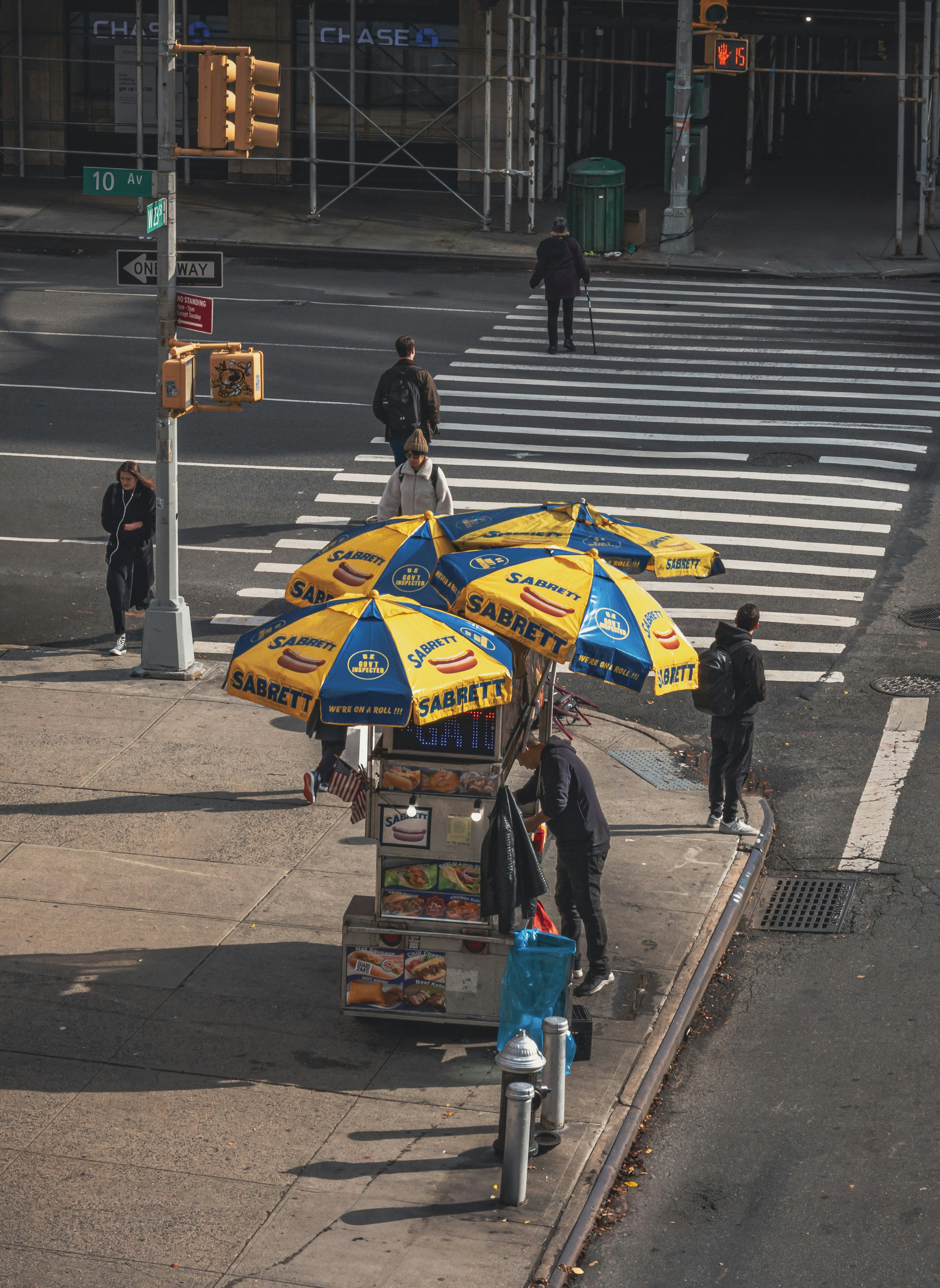 Hot dog stand busy on a city sidewalk.