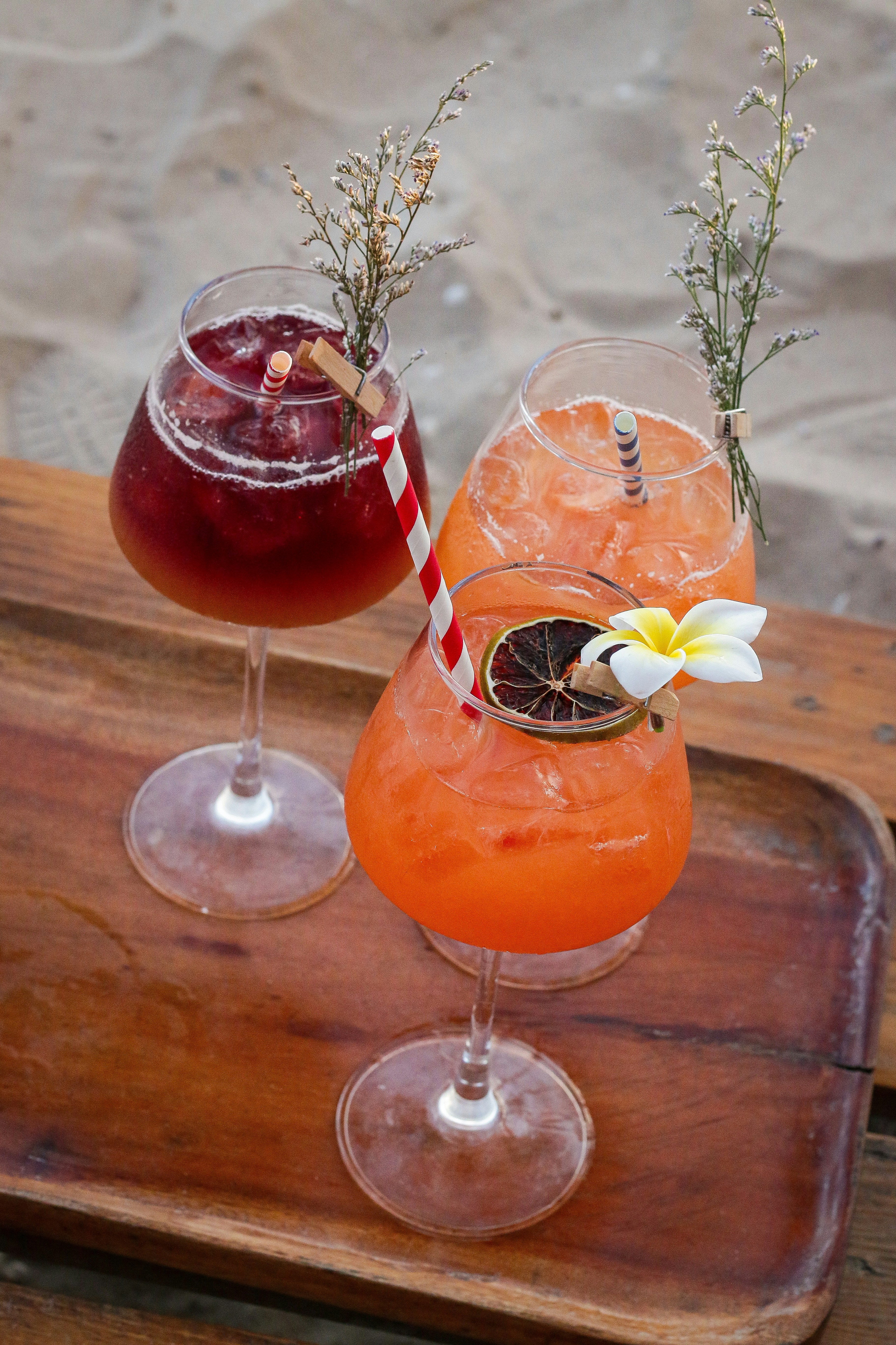 Three cocktails are served on a wooden tray.