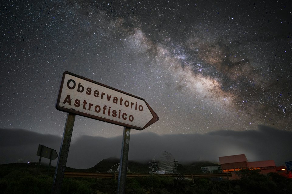 The Milky Way arcing over a Canary Islands observatory sign on a clear night