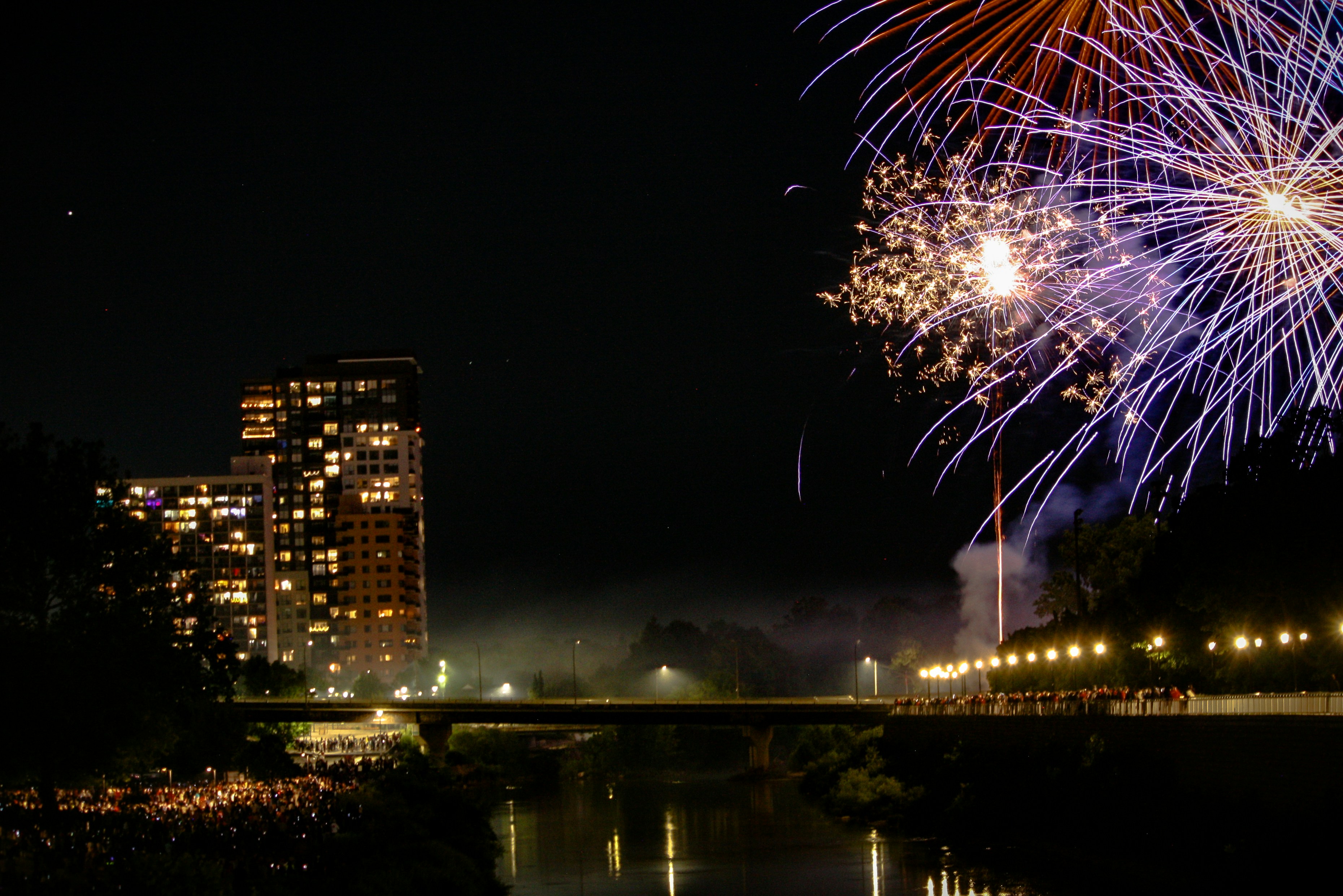 Fireworks explode over a city at night.
