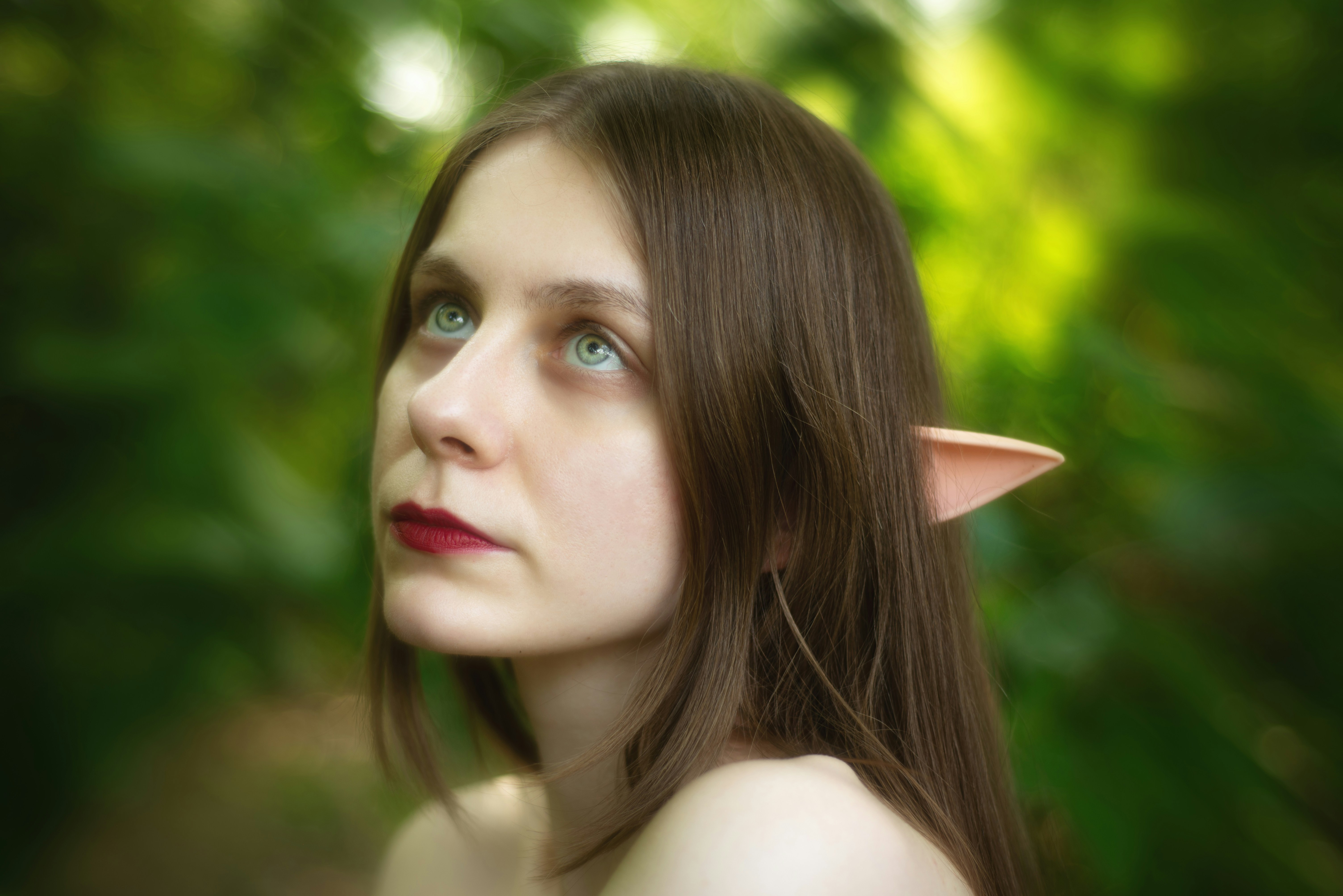 A woman with pointed ears looks towards the sky.