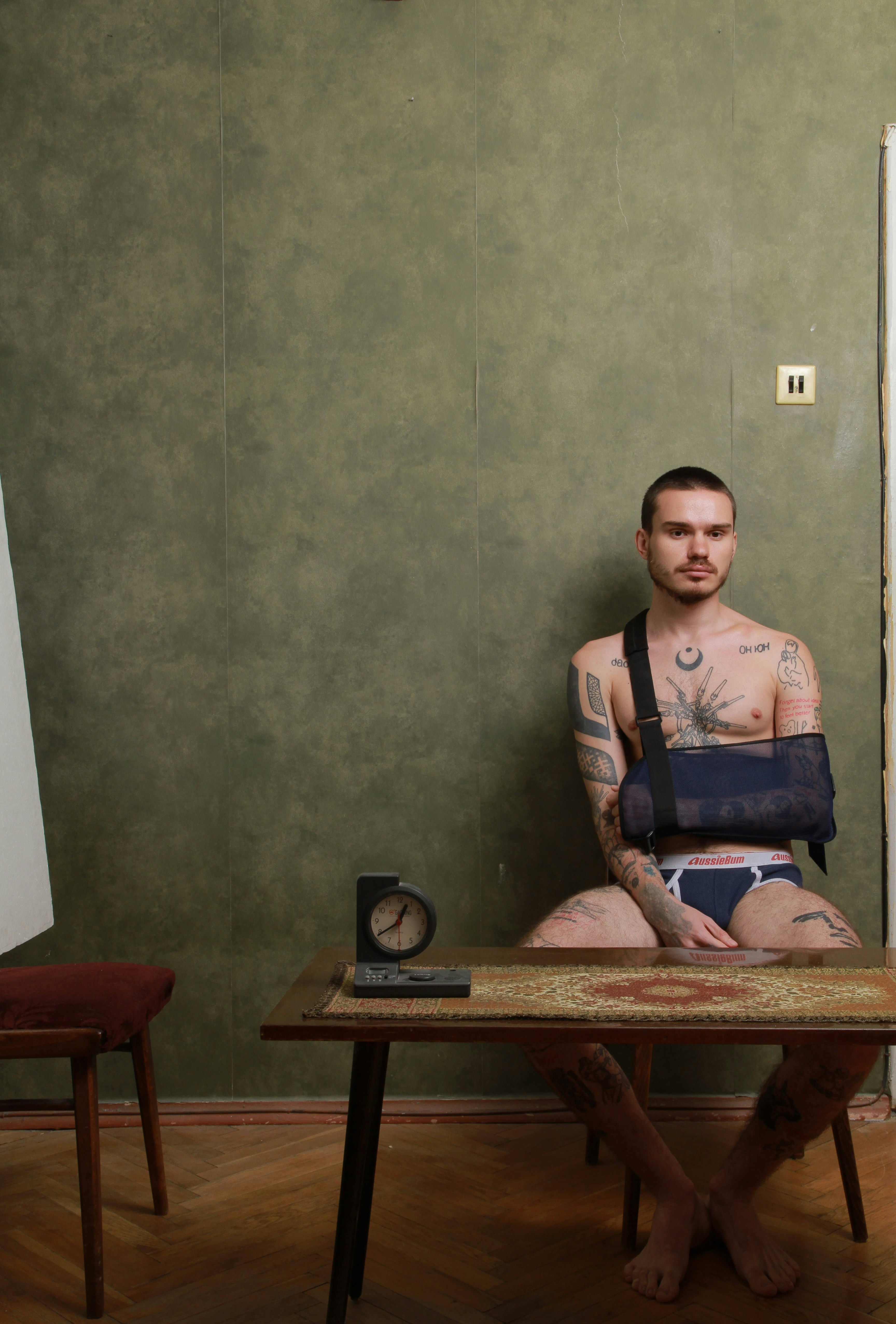 腕を吊り下げた男がテーブルに座っています。