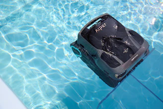 A robotic pool cleaner is working in the water.
