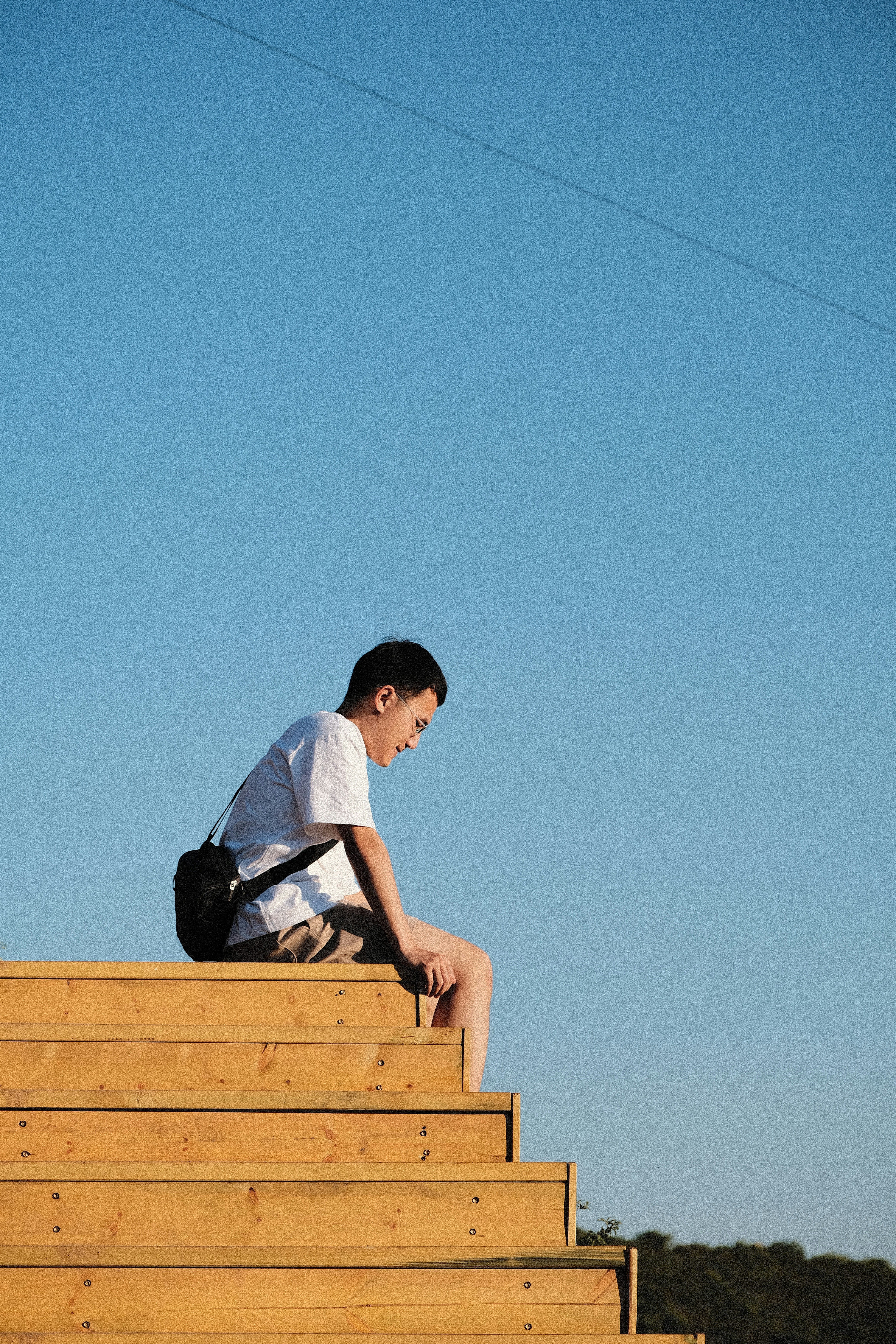 Man sits on wooden steps, looking down.