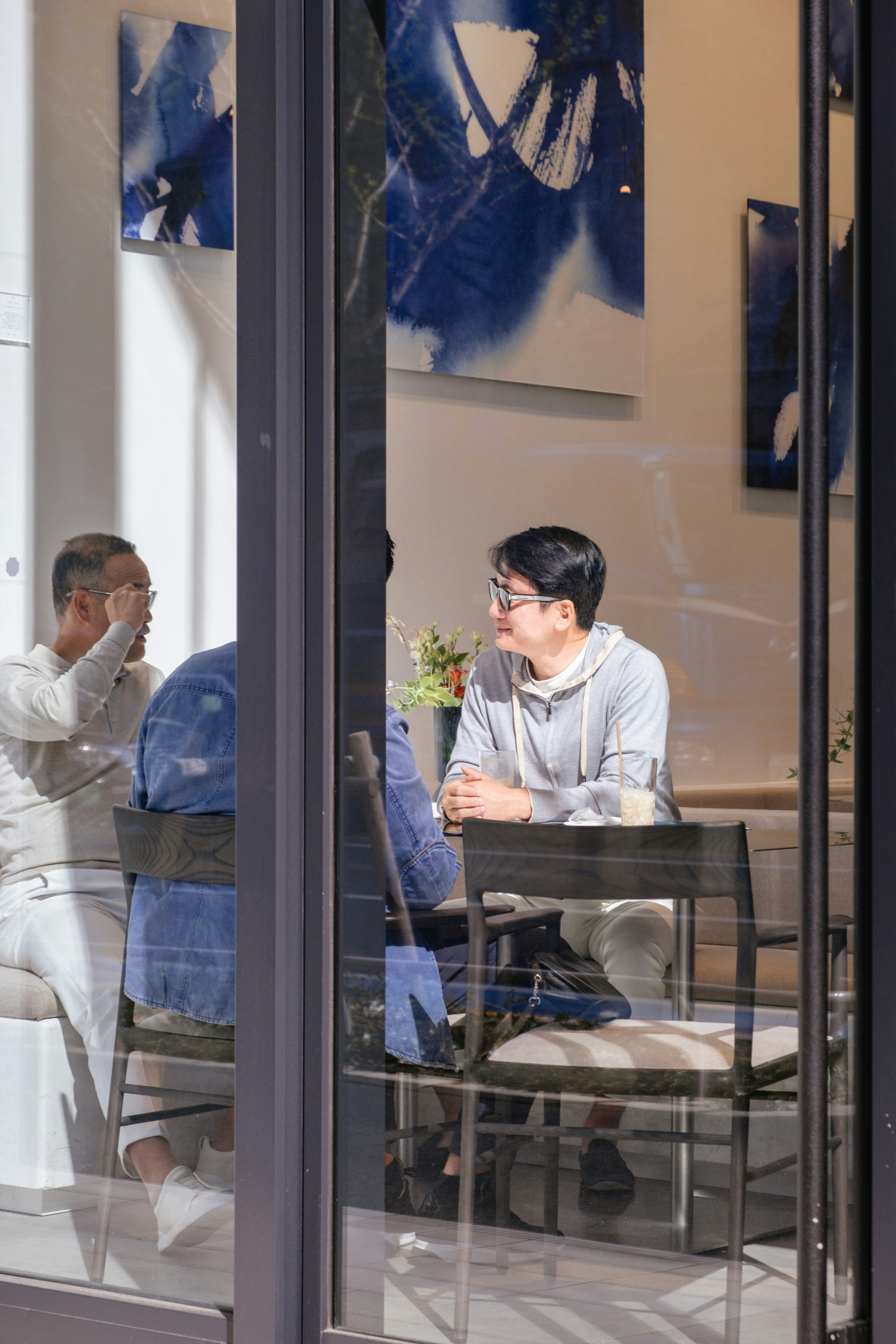 People are seen through a window, inside a cafe.