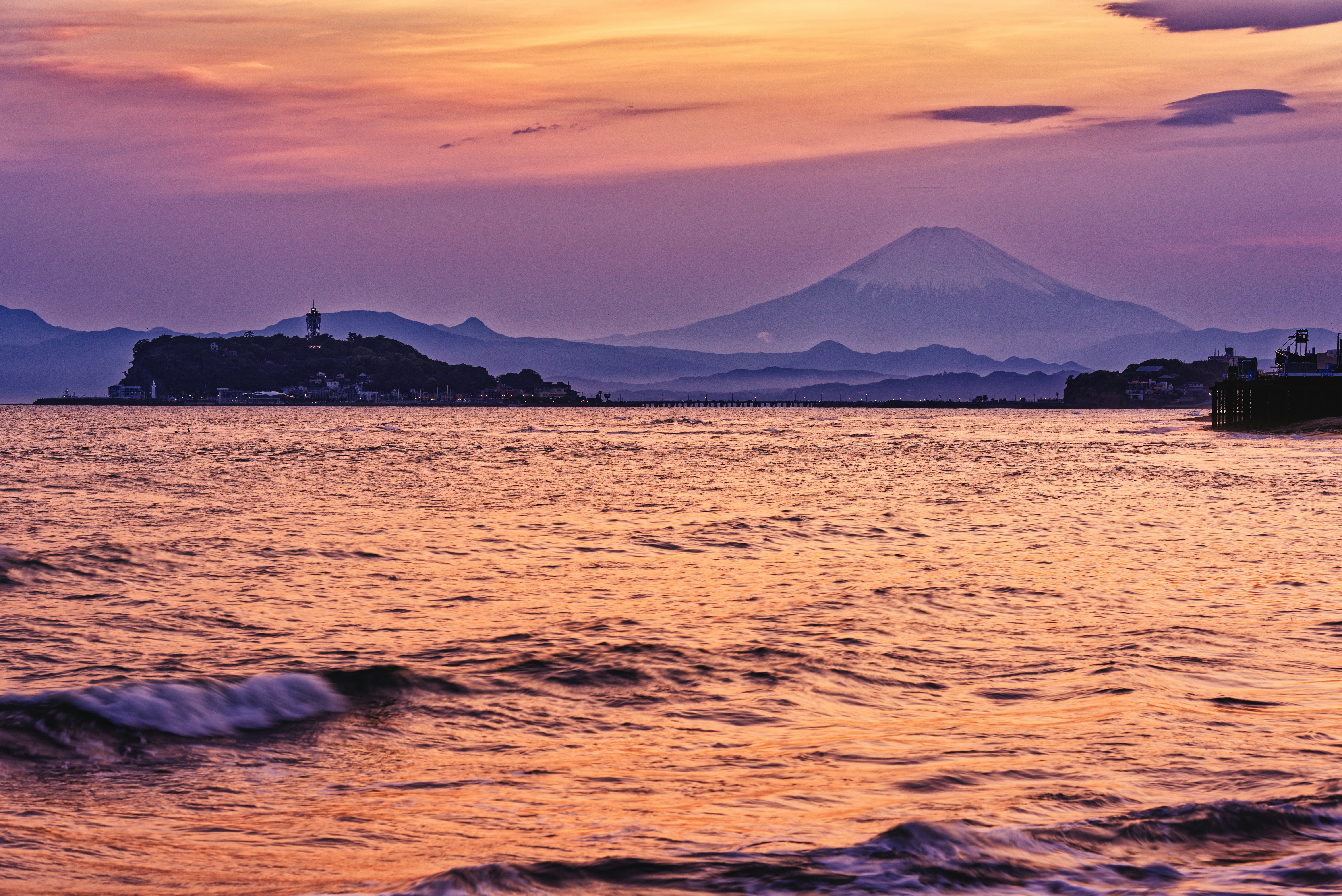Sunset over the ocean with mountains in view.