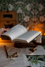 A hand opens a book with cozy and antique décor.