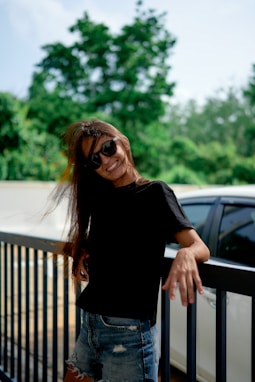 Smiling woman leans on a fence with her hair blowing.