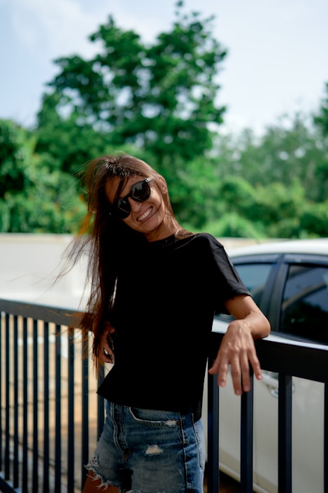 Smiling woman leans on a fence with her hair blowing.