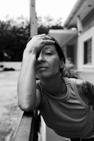 Woman rests her arm on a railing, looking serious.