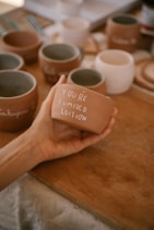 A hand holds a terracotta pot with a message.