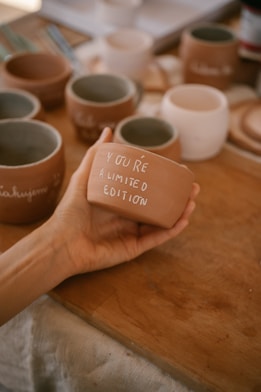 A hand holds a terracotta pot with a message.