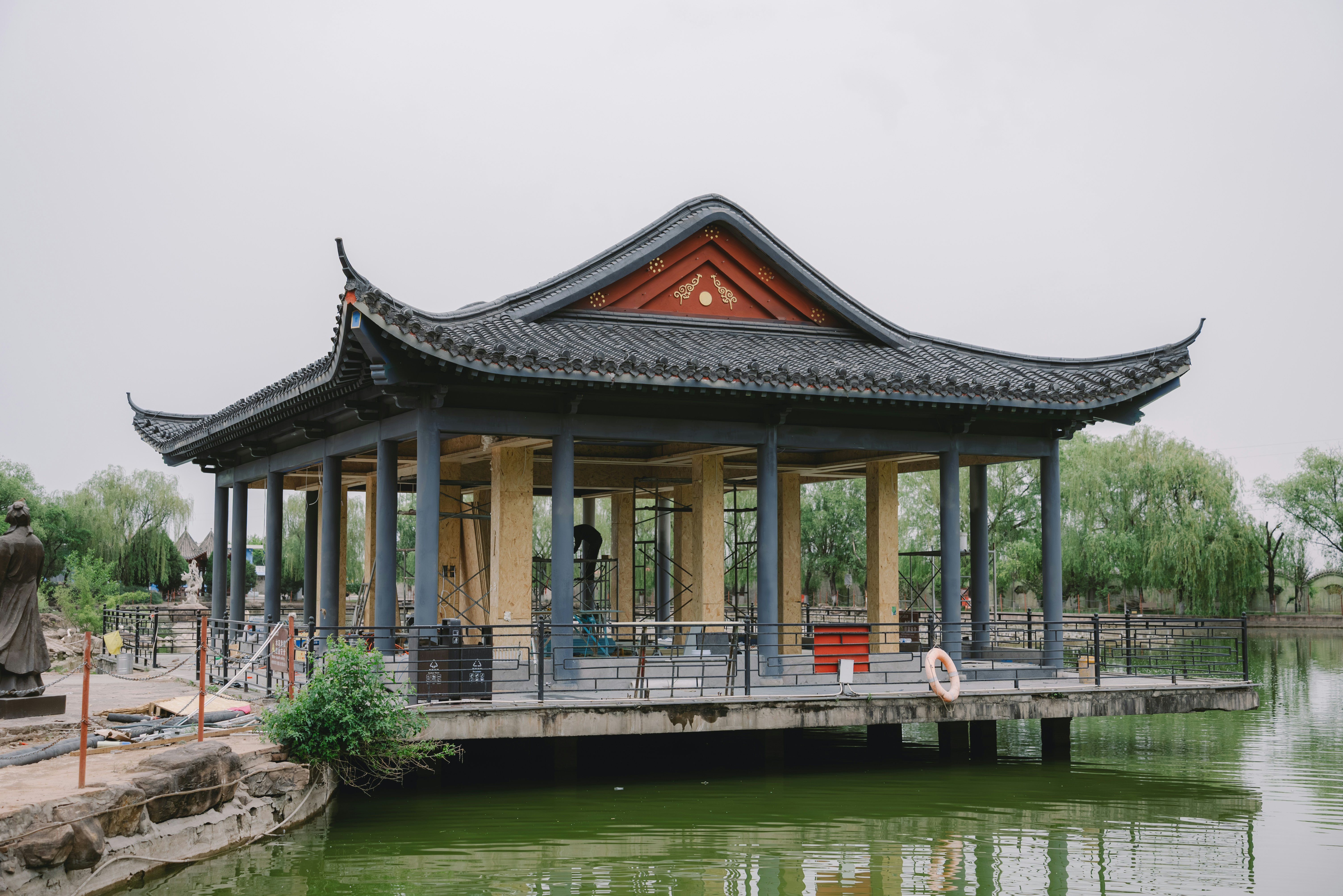 A chinese pavilion sits peacefully by a lake.