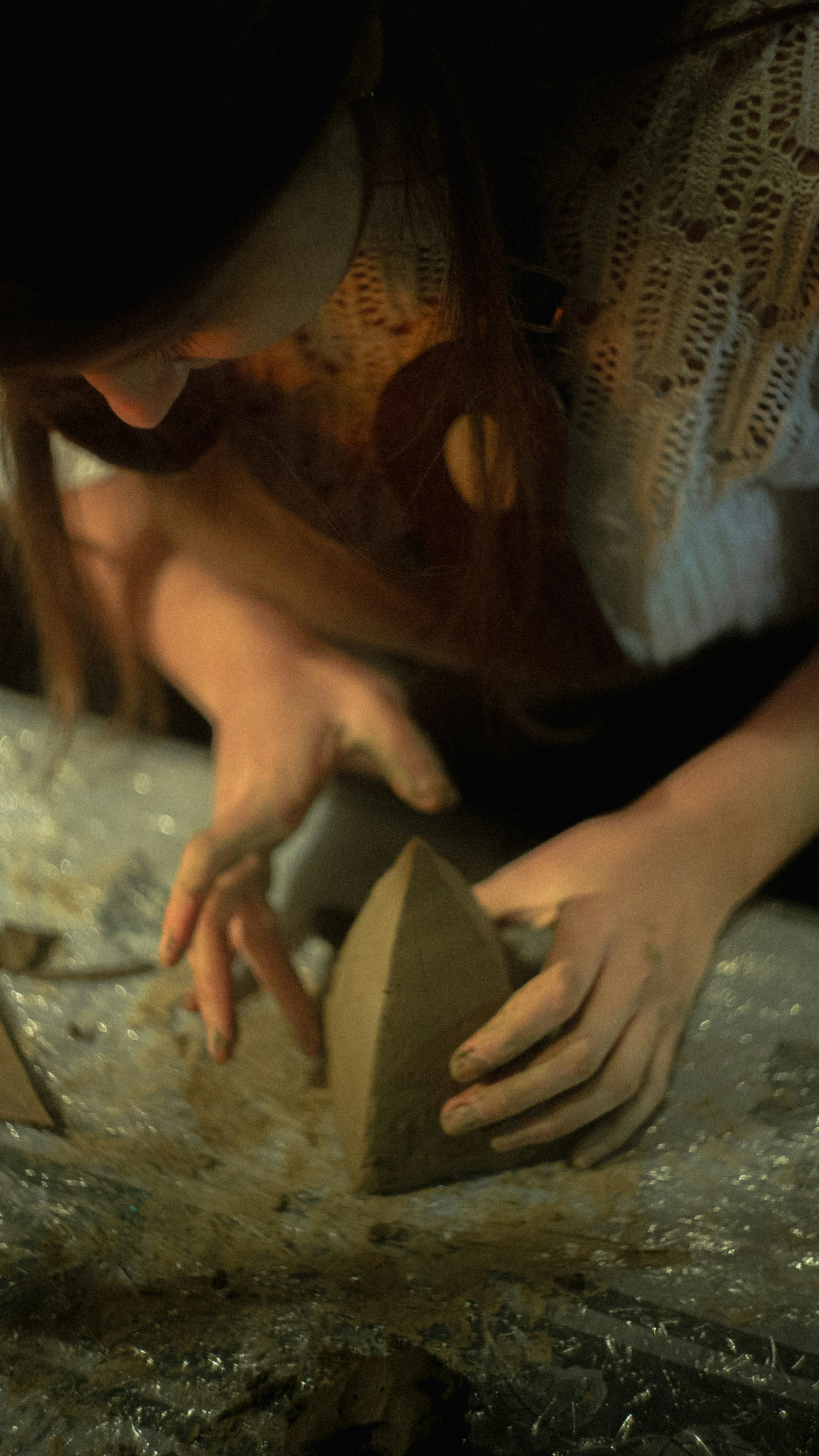 A person sculpts clay into a triangular shape.
