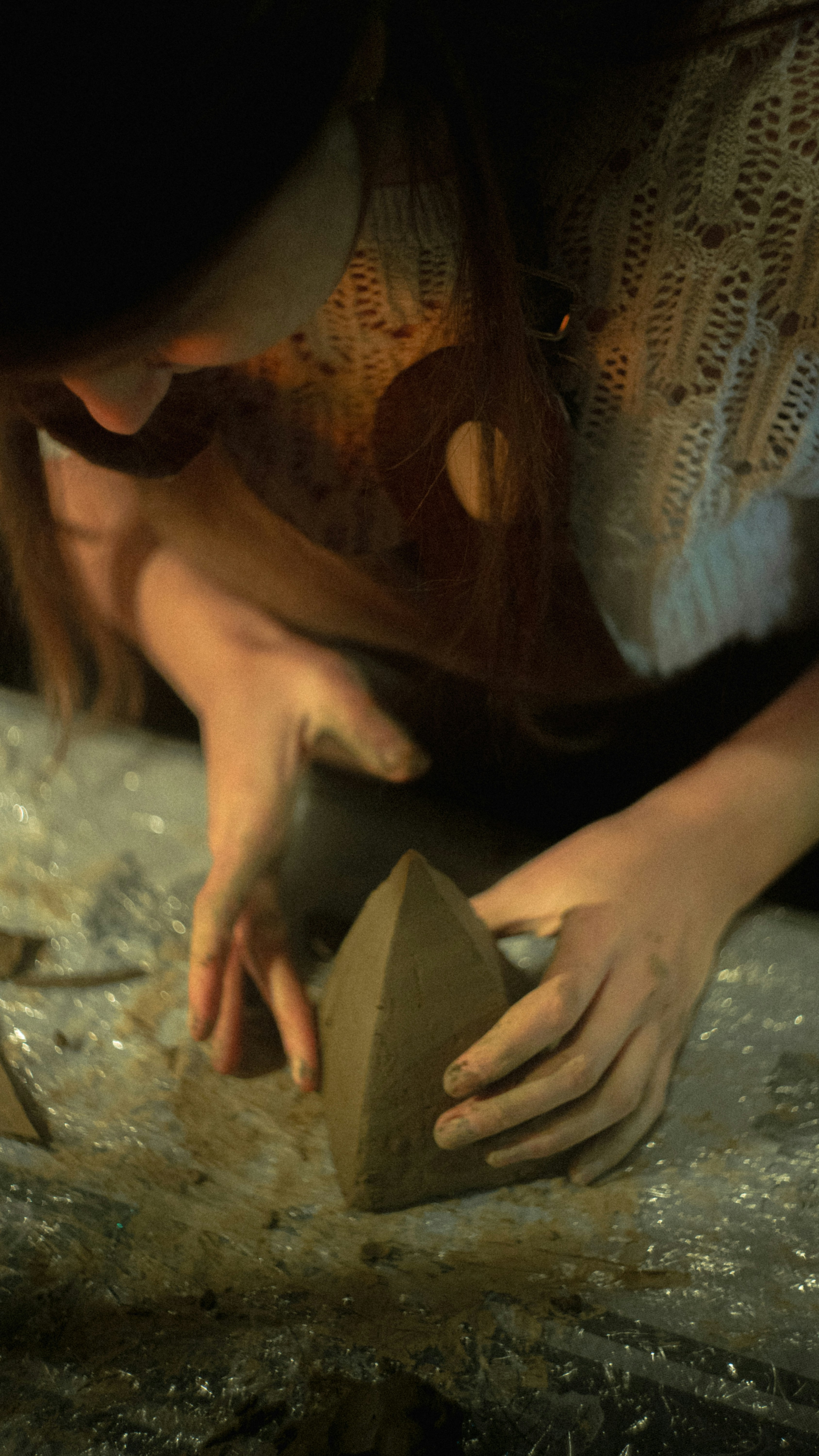 Woman is shaping clay into a pointed form.
