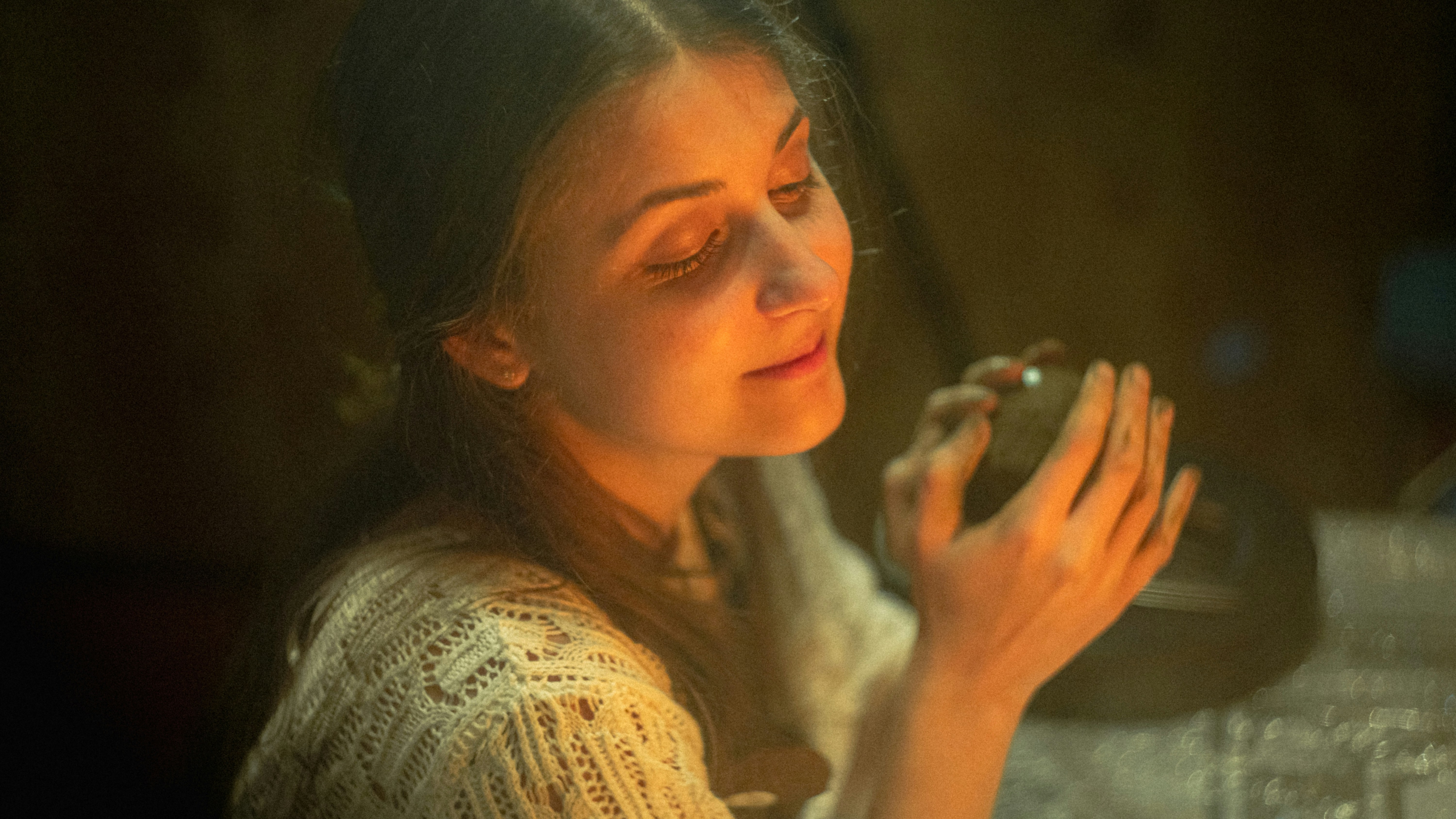 A woman smiles while holding a small orb.