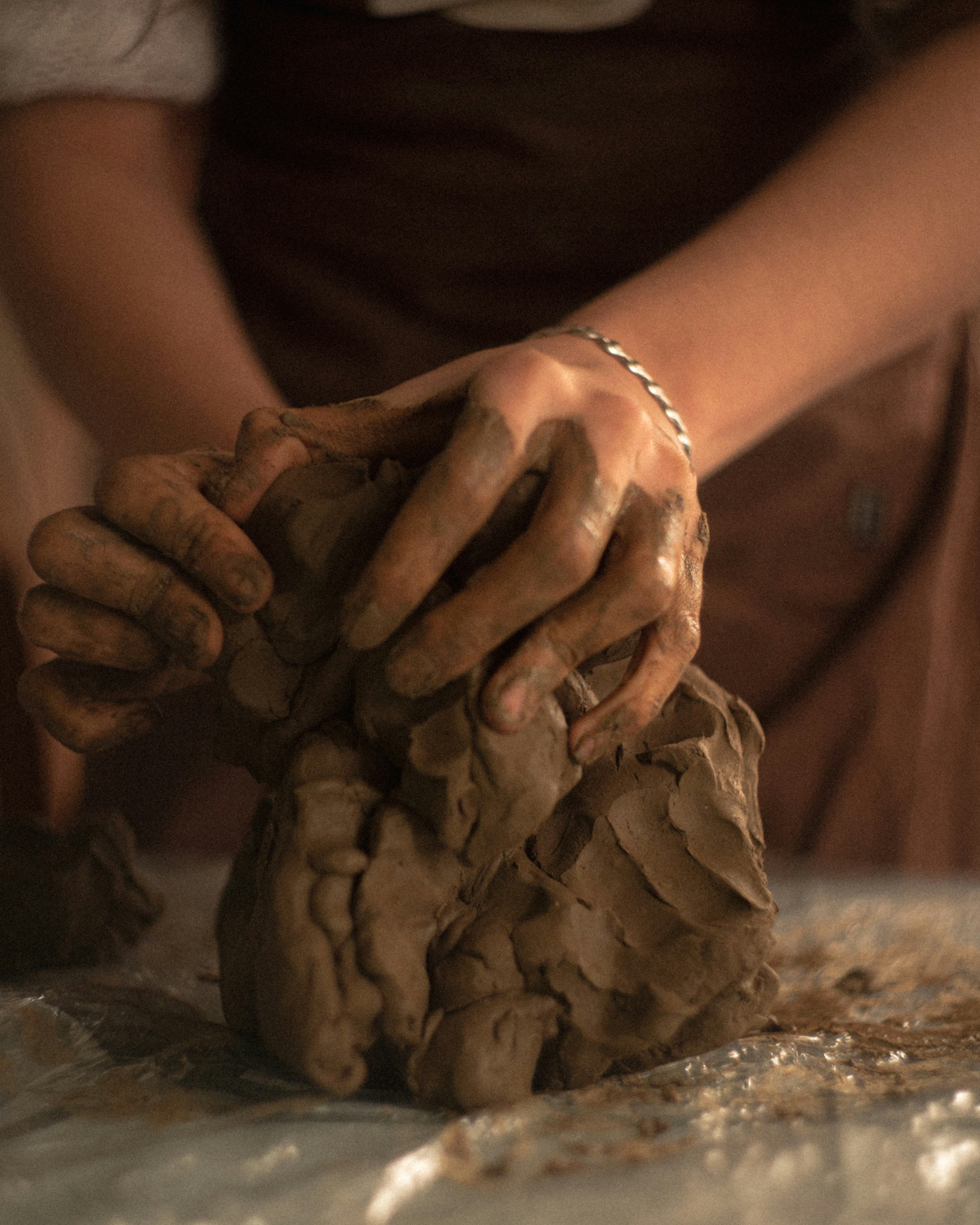 Hands mold clay into a sculpture.