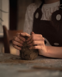 A person shapes clay with their hands.