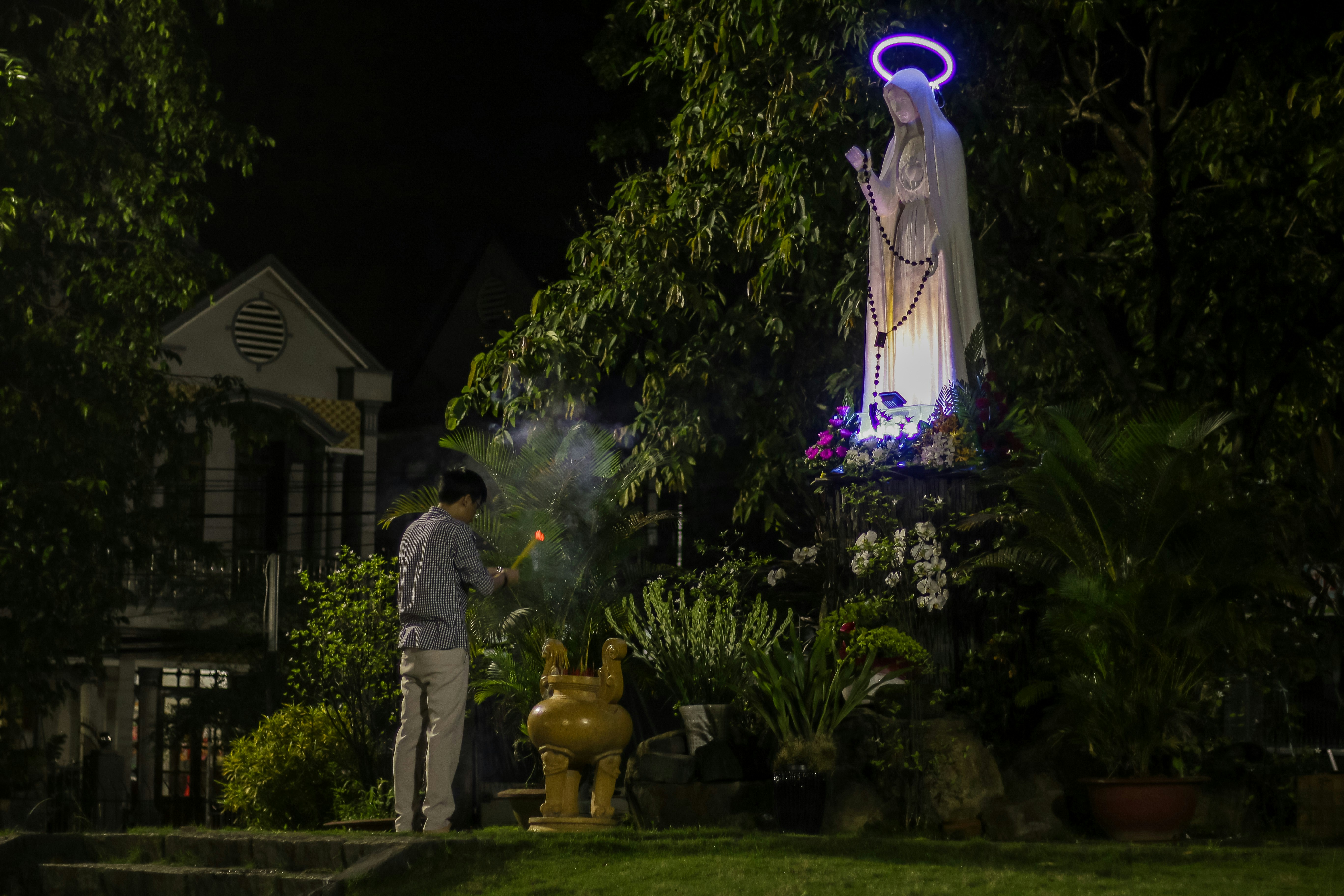 A person prays before a statue at night.