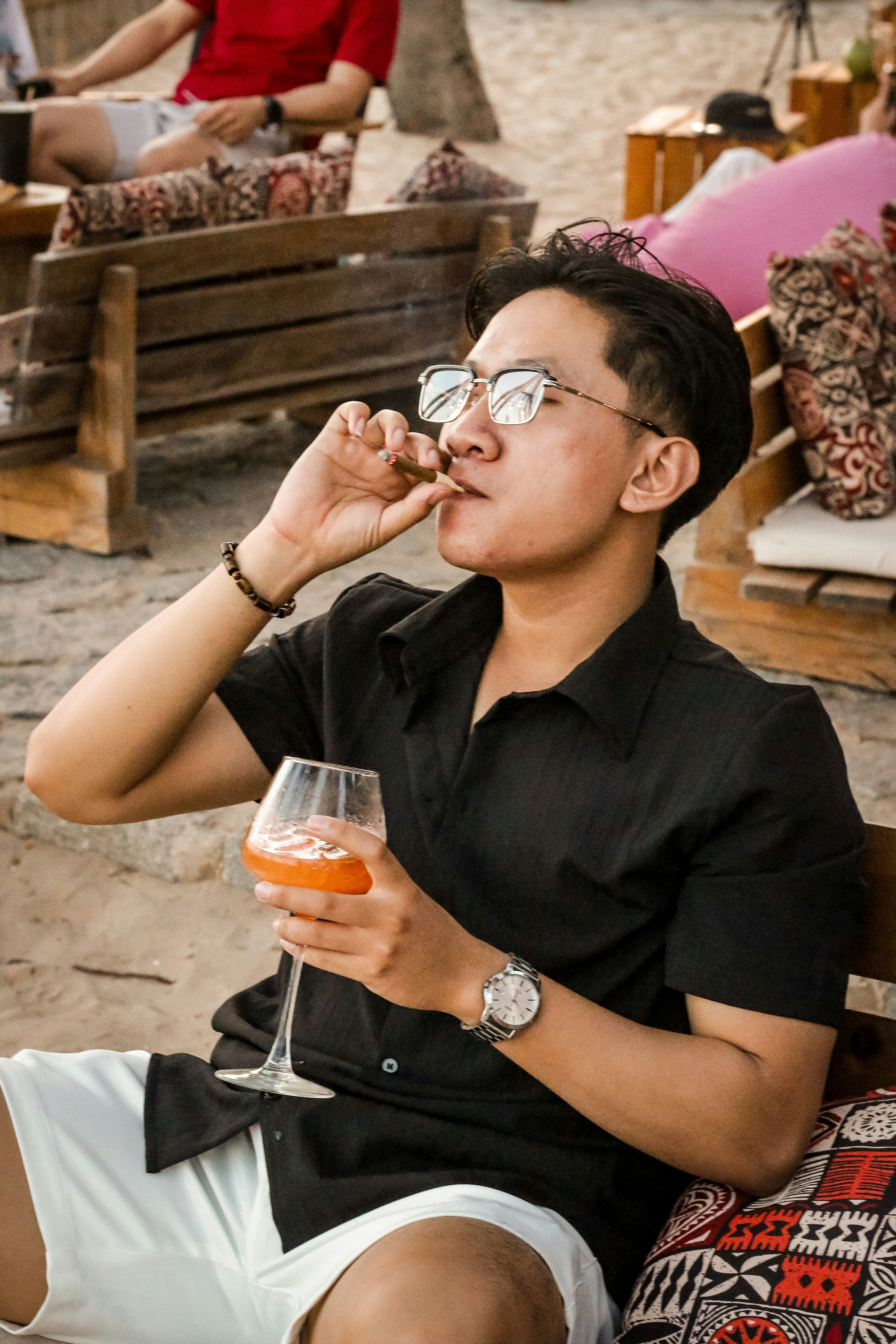 Man smokes and drinks on the beach.