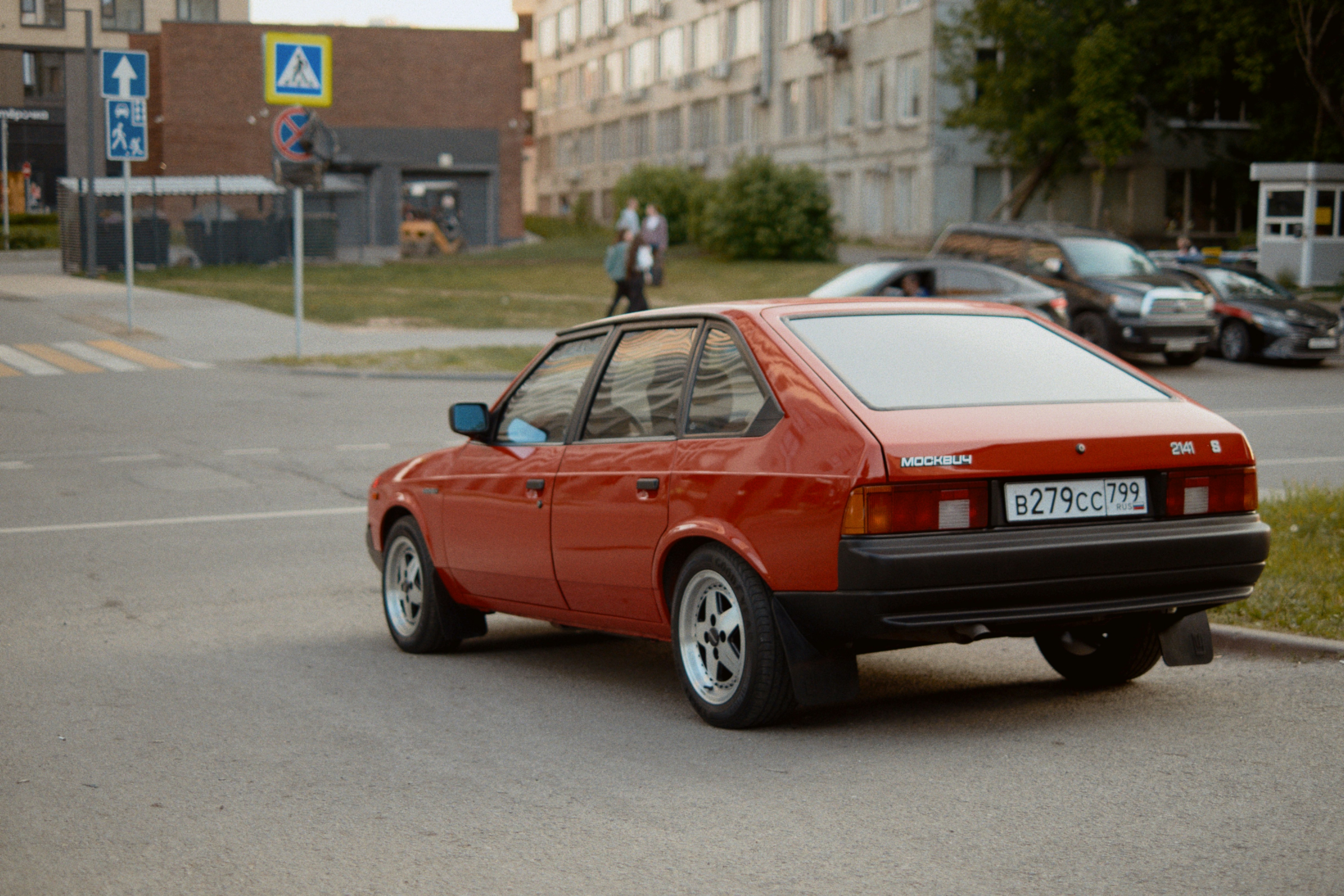 A red car is parked on a city street.