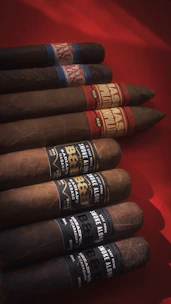 Several cigars are arranged on a red surface.