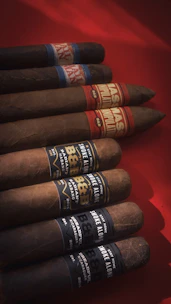 Several cigars are arranged on a red surface.