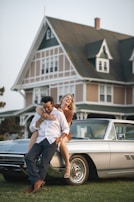 A couple poses on a vintage car.