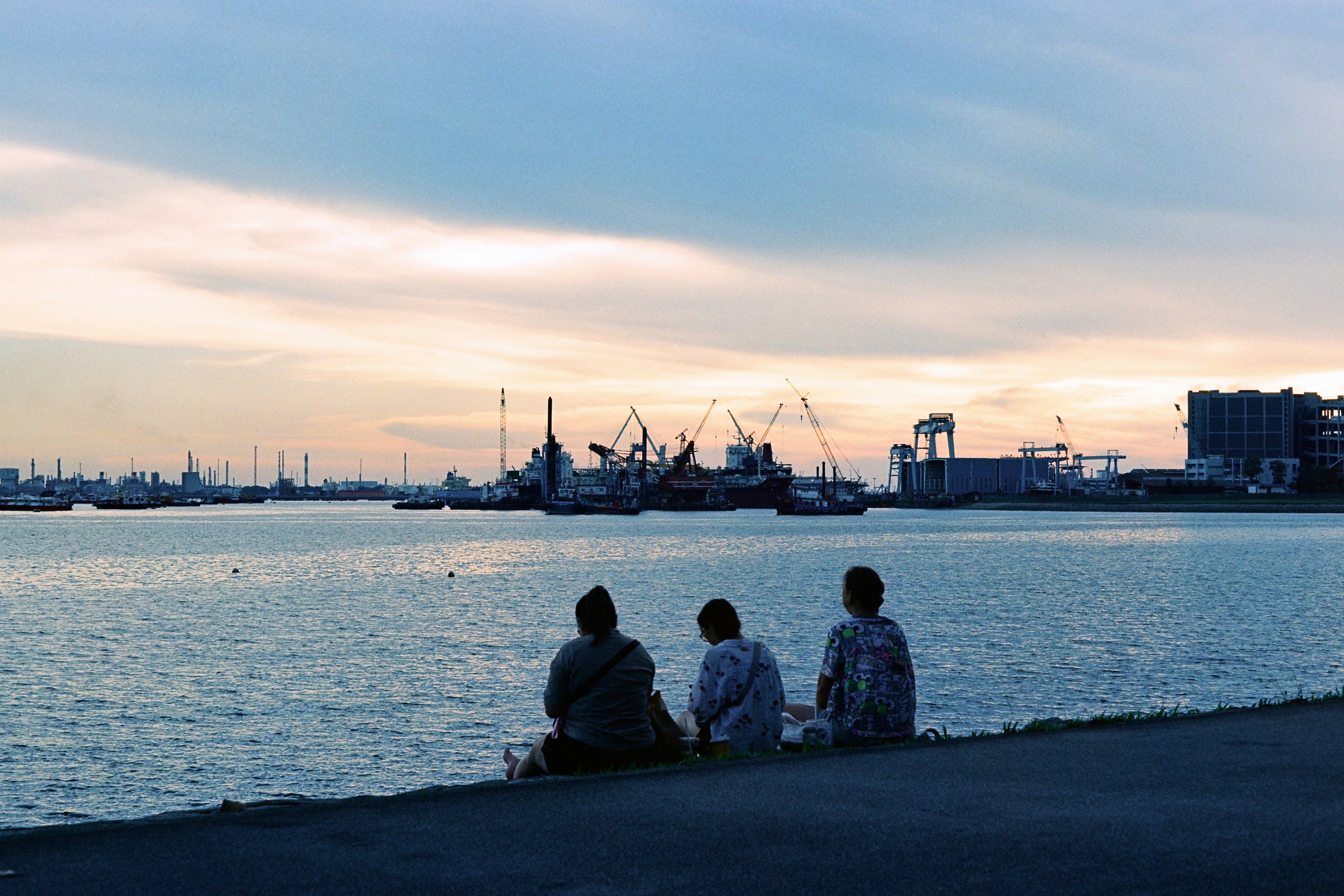 People watch the sunset over a tranquil harbor.