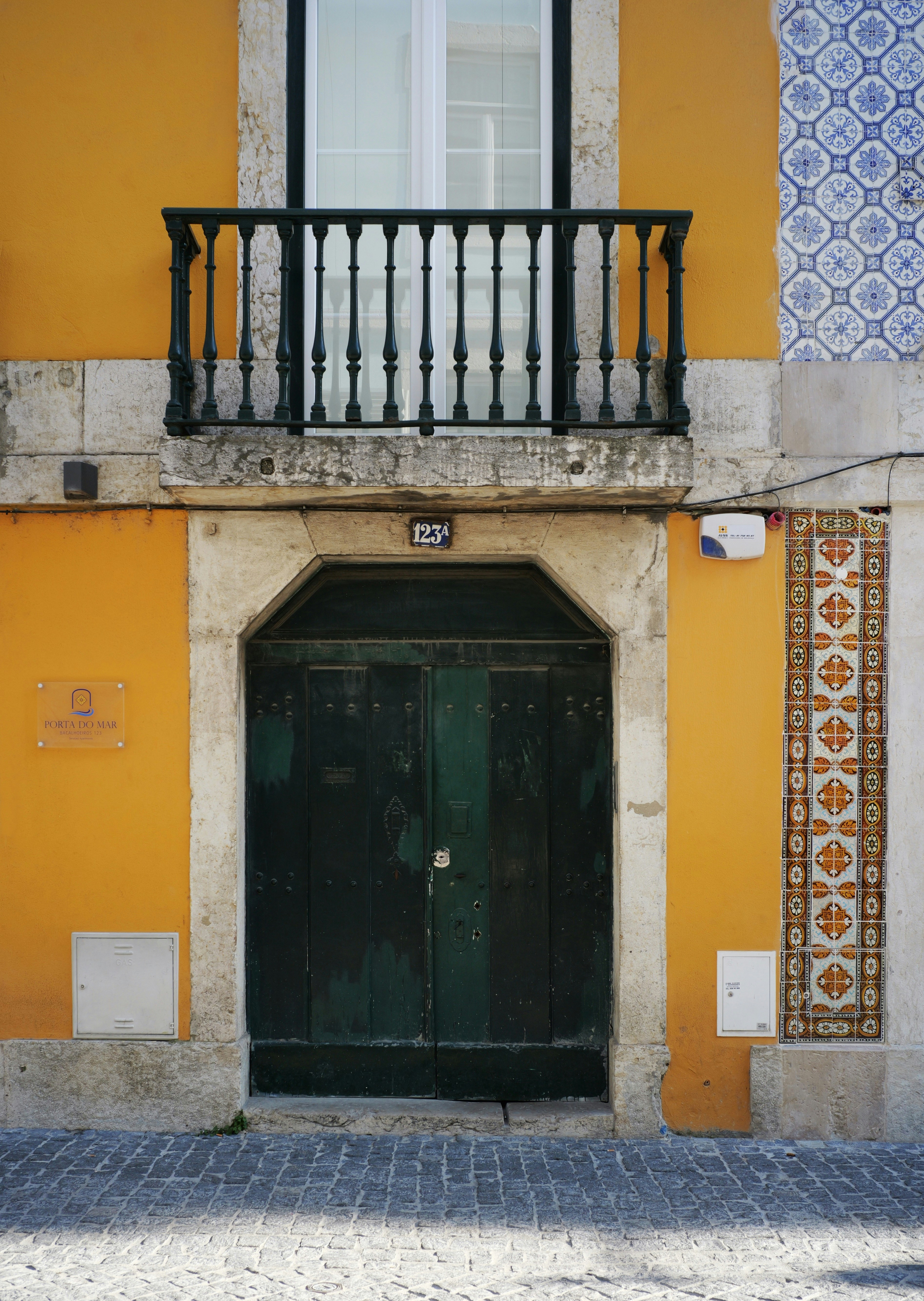 Yellow building with balcony and green door.