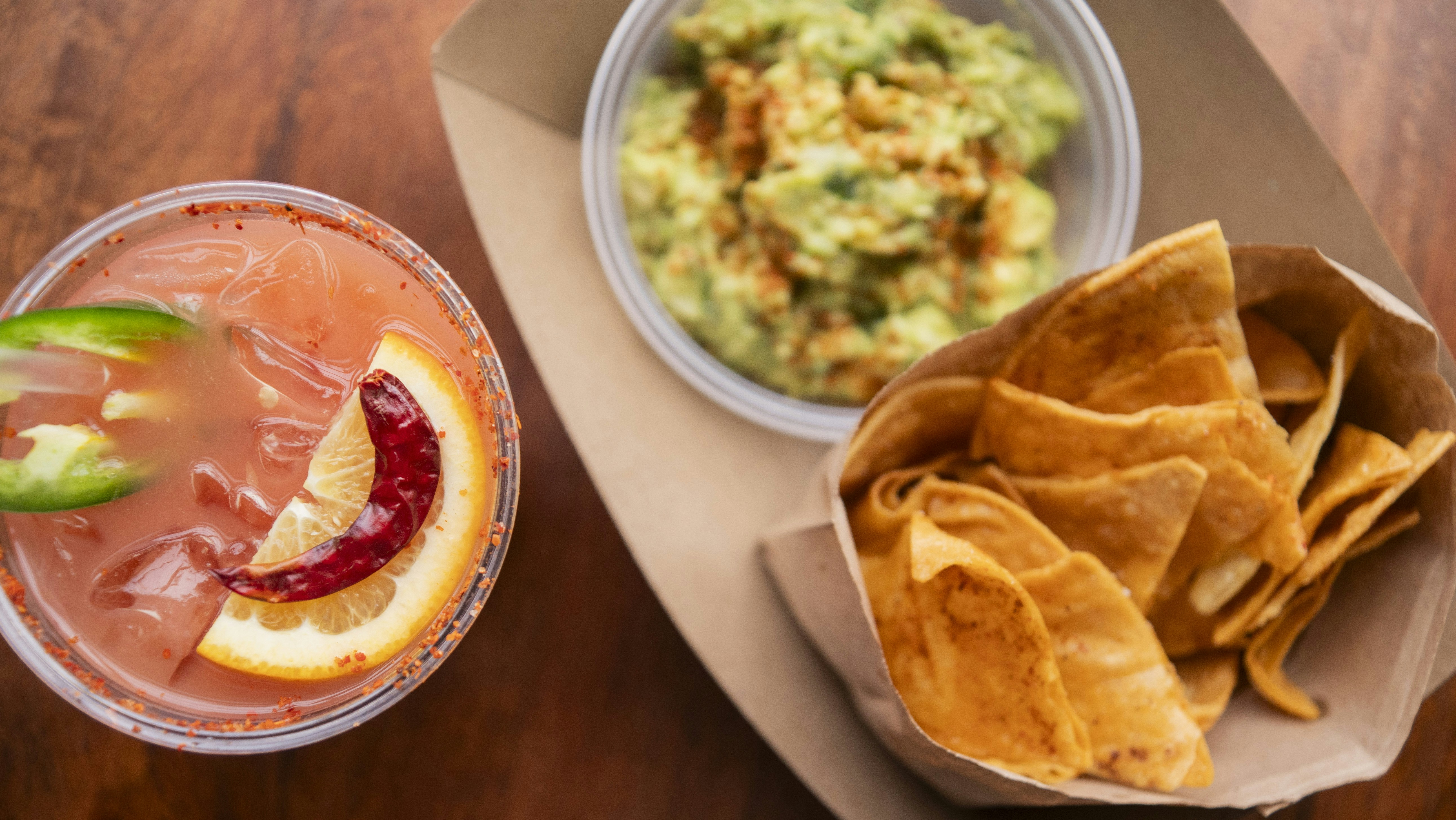 Refreshing drink, chips, and guacamole on a table.