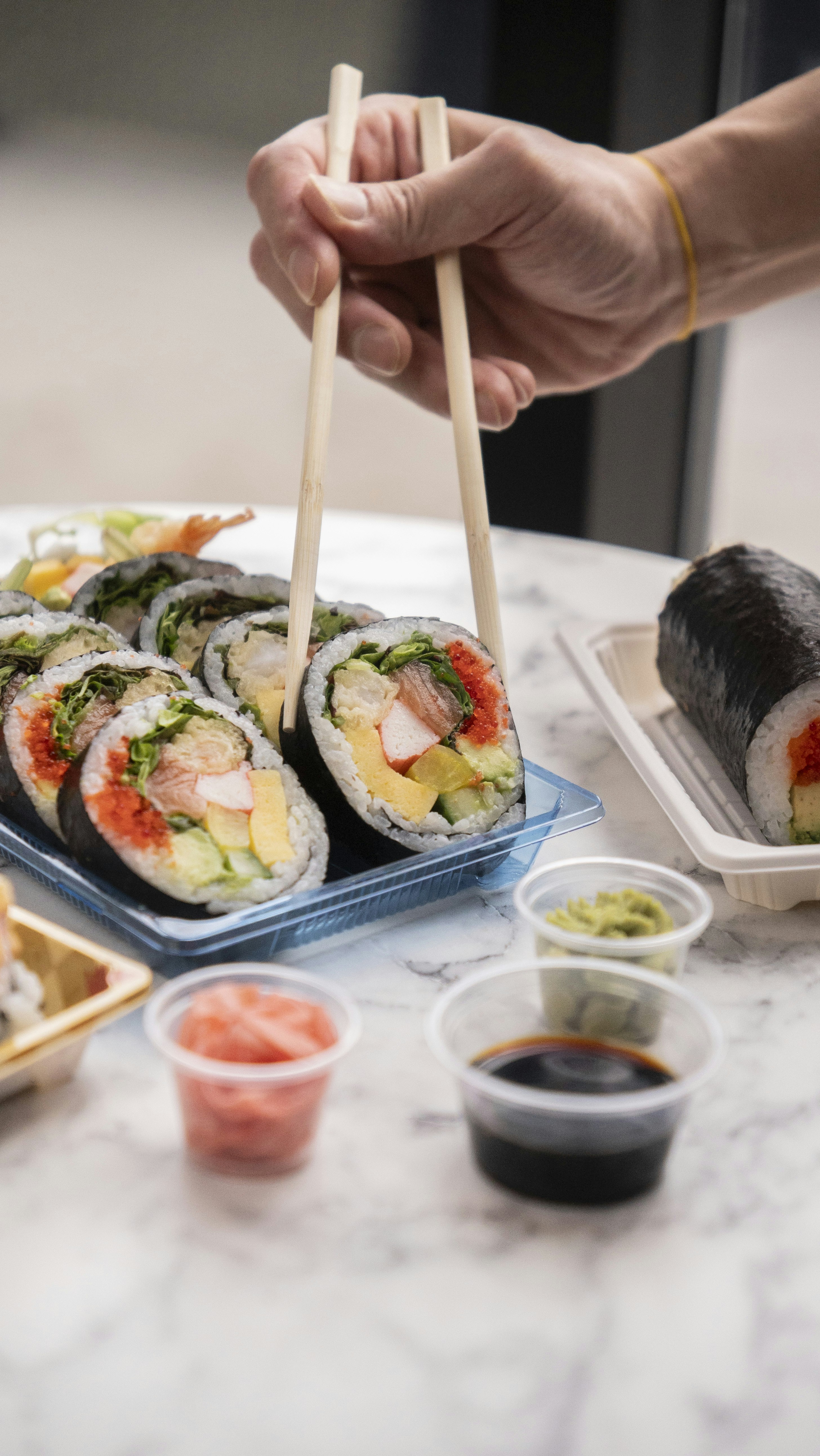 Alguém usando pauzinhos para comer sushi.