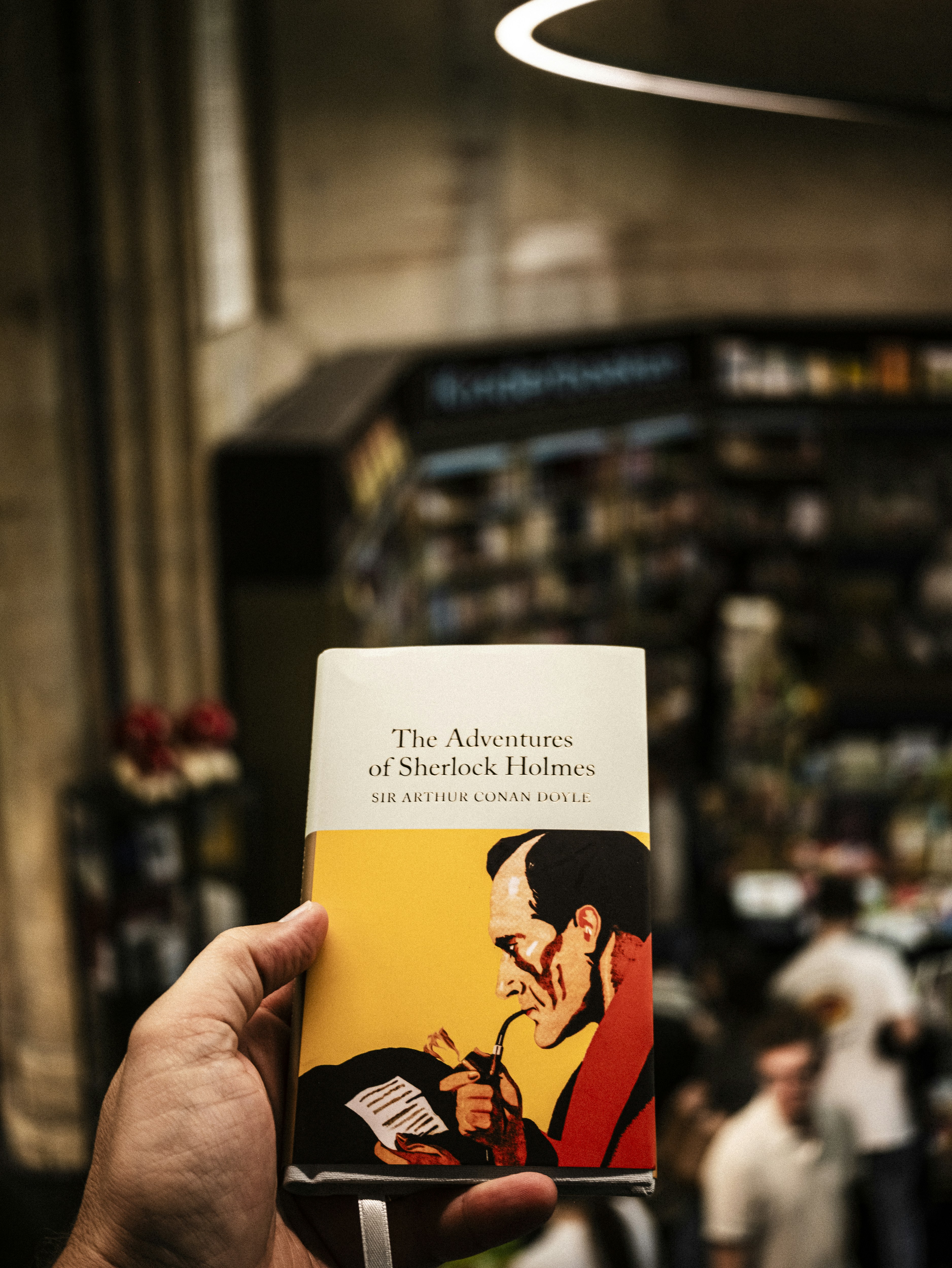 Una persona tiene in mano il libro "Le avventure di Sherlock Holmes".