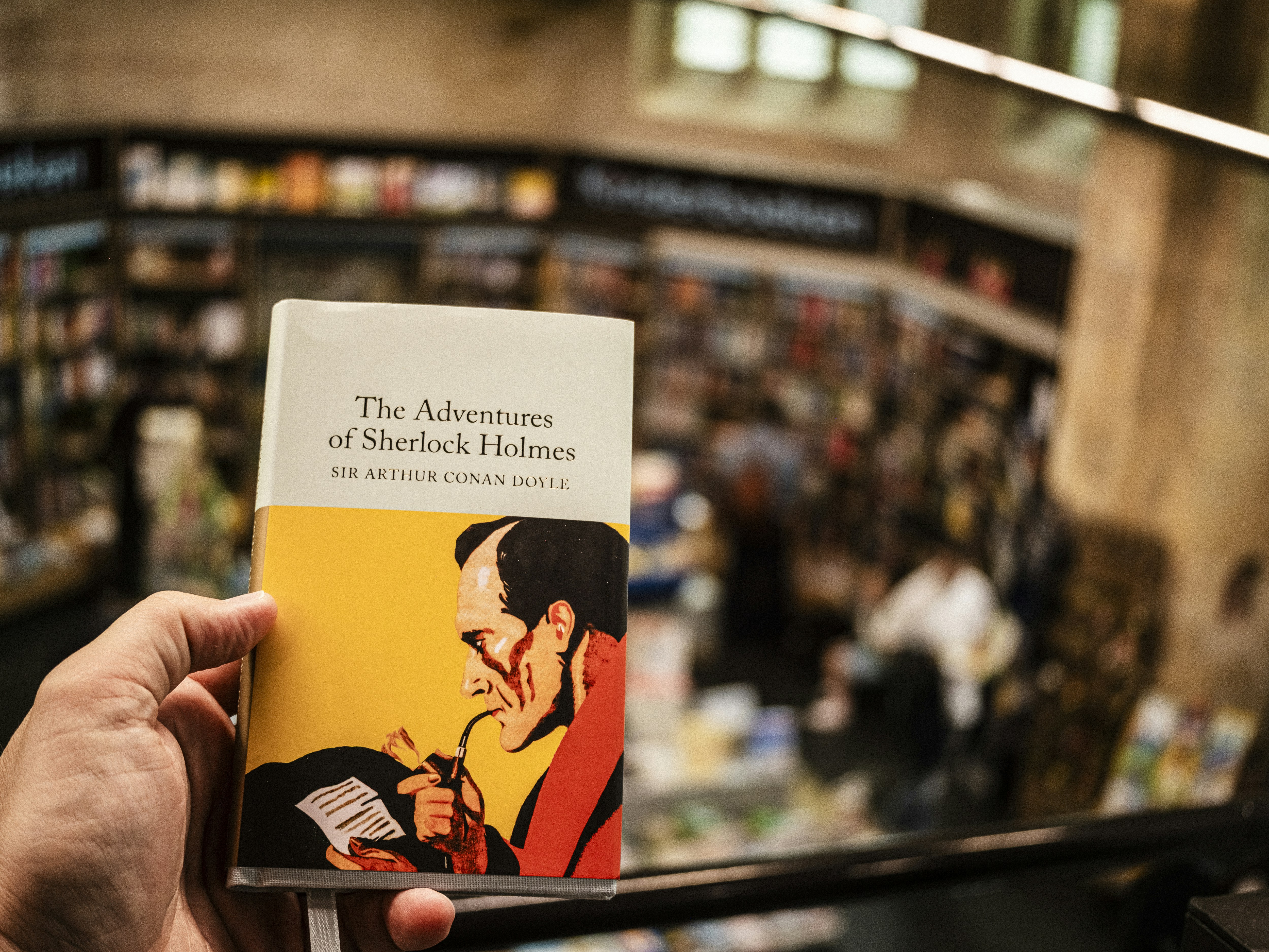 Tenendo in mano "Le avventure di Sherlock Holmes" in una libreria.