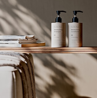 Shampoo and conditioner sit on a wooden shelf.