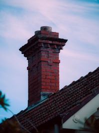 A red brick chimney against a blue sky.