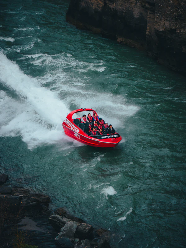 A red jet boat throwing spray on a river