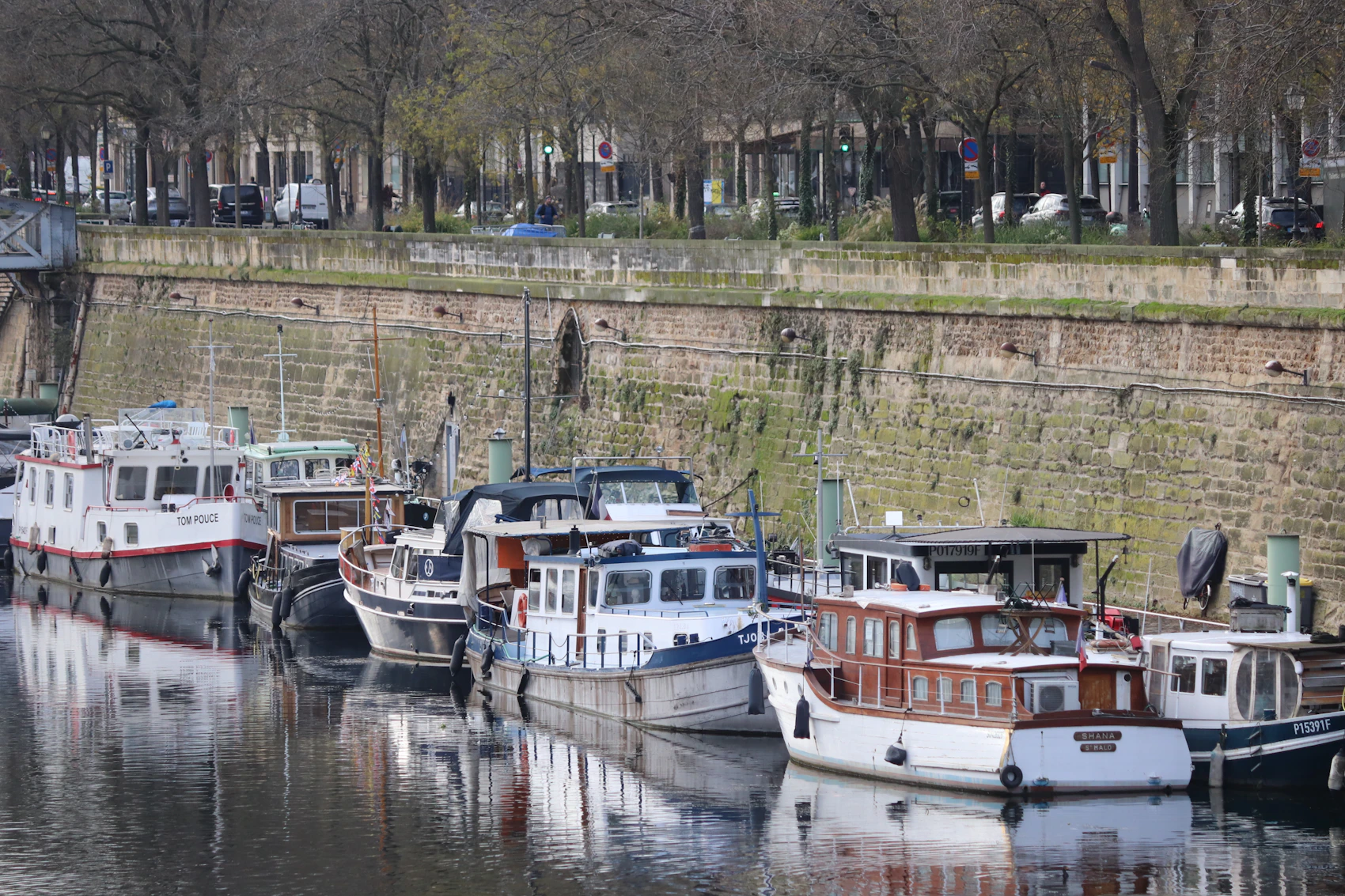 Boats moored beside leafy paths on Canal Saint-Martin in Paris