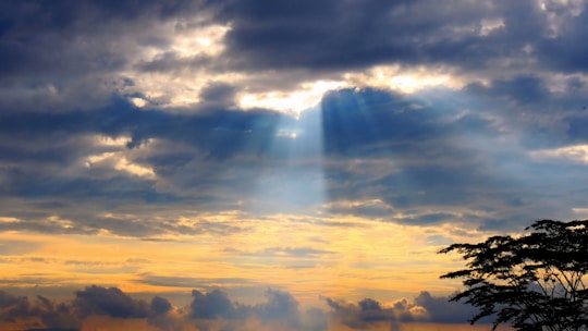 God rays burst through a cloudy sky.