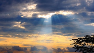 God rays burst through a cloudy sky.