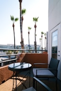 A balcony offers outdoor seating with palm trees.