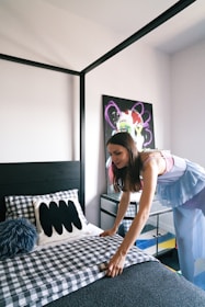 Woman makes the bed in a stylish, modern bedroom.