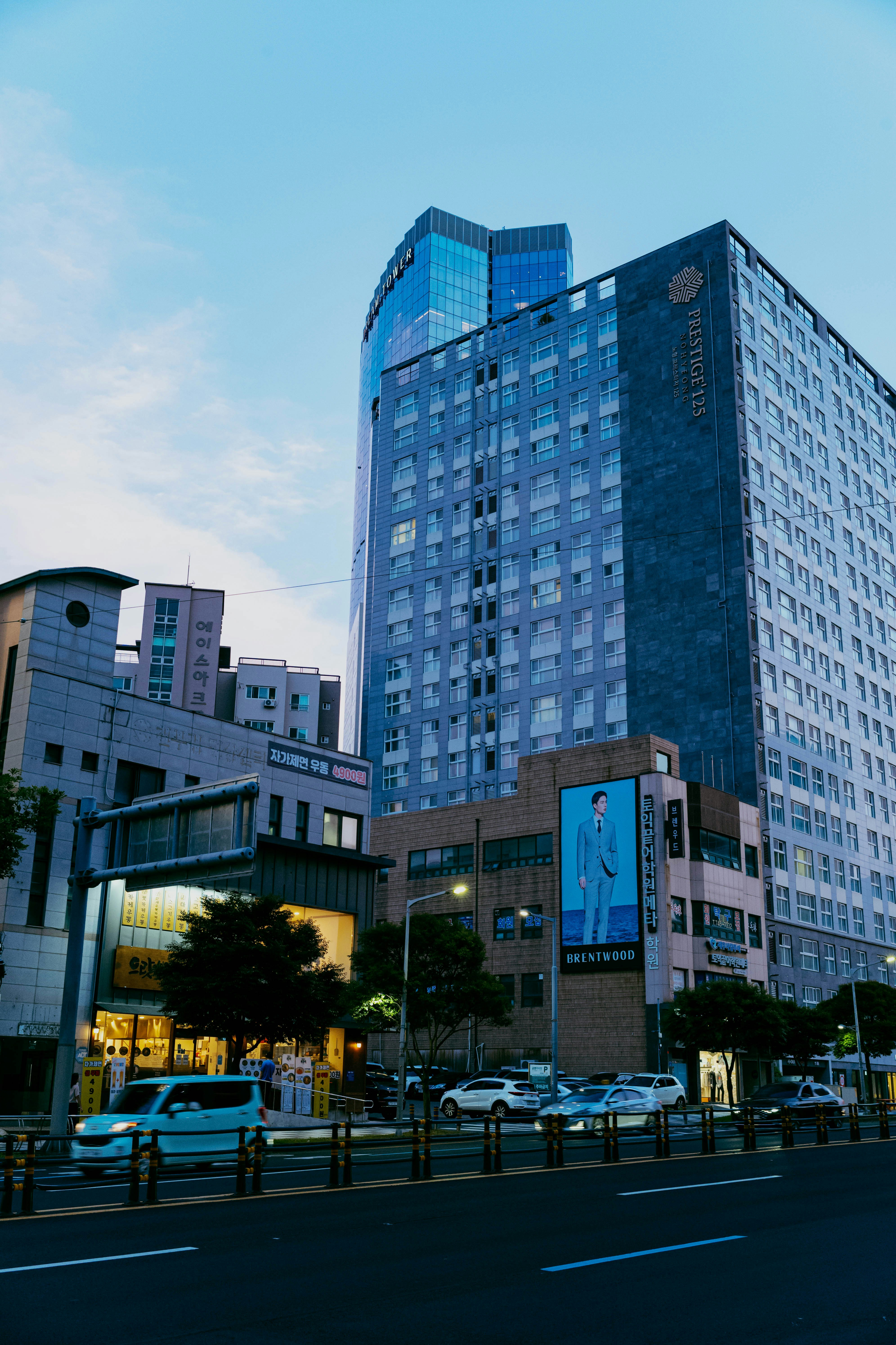 City buildings stand beneath a blue, cloudy sky.