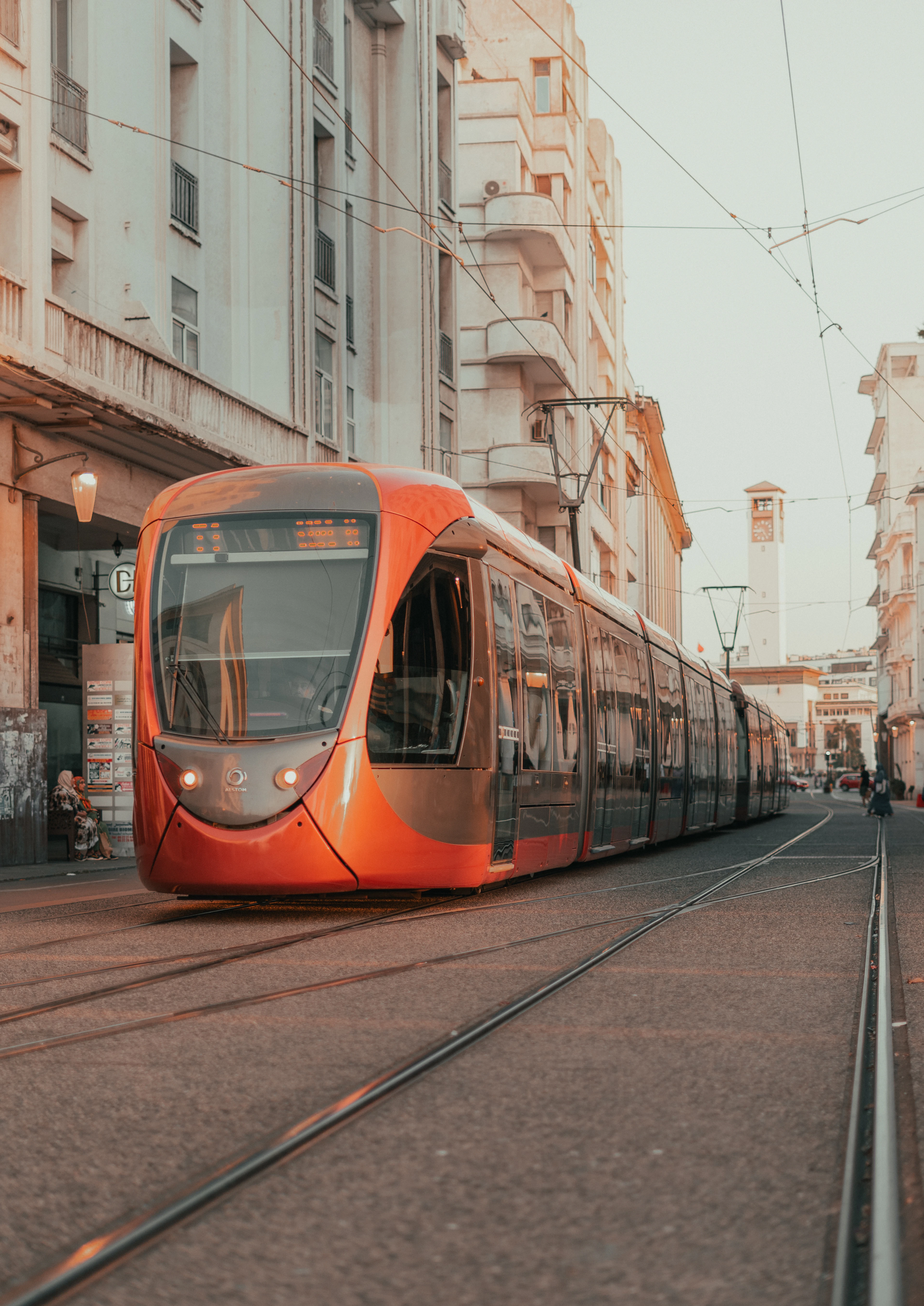 An orange tram rolls down a Casablanca street between pale buildings at sunset.