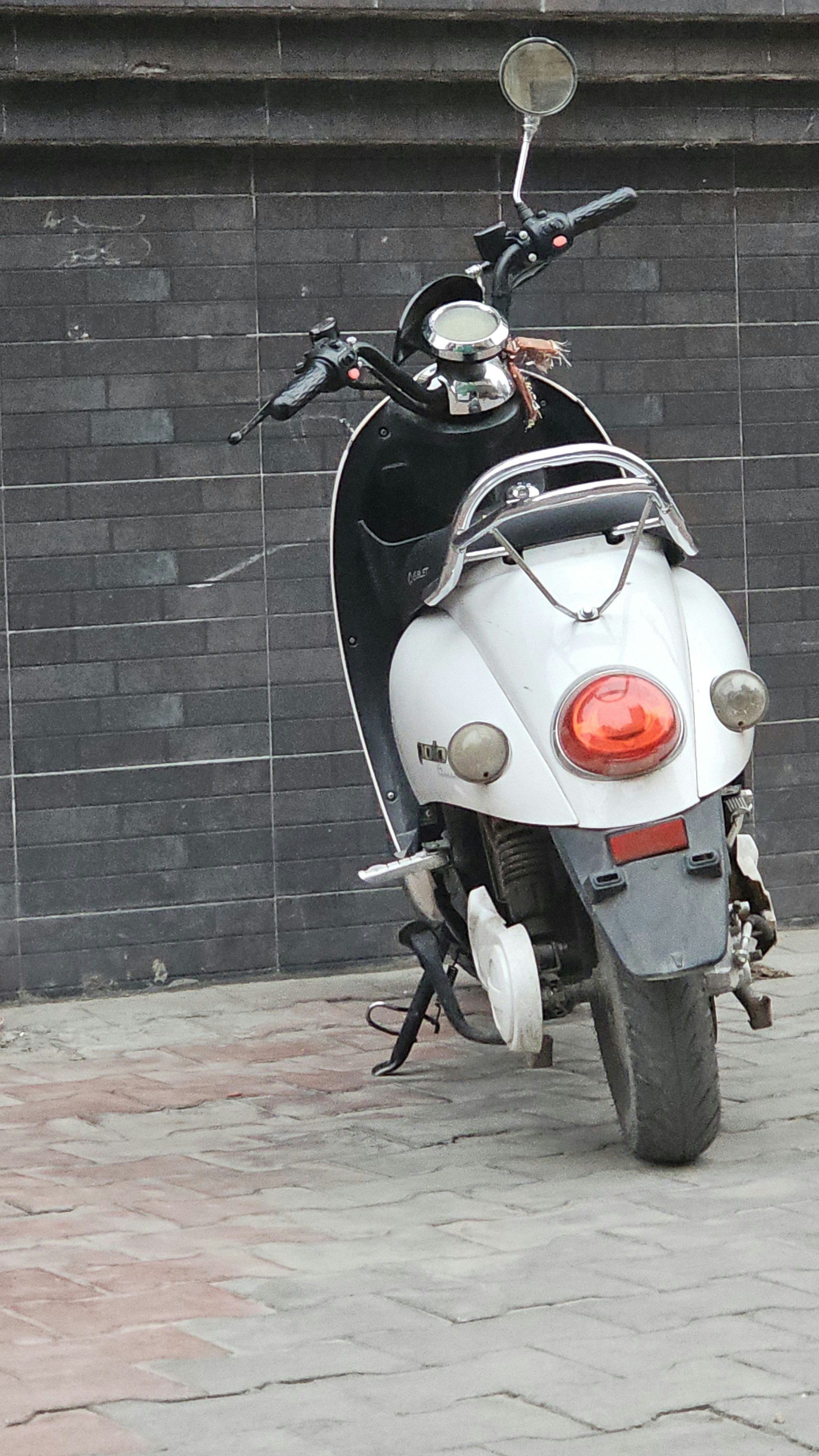 A white scooter is parked next to a wall.