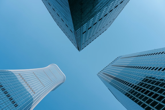 Three skyscrapers point upward against the blue sky.